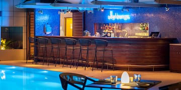 a bar with chairs and a pool at night