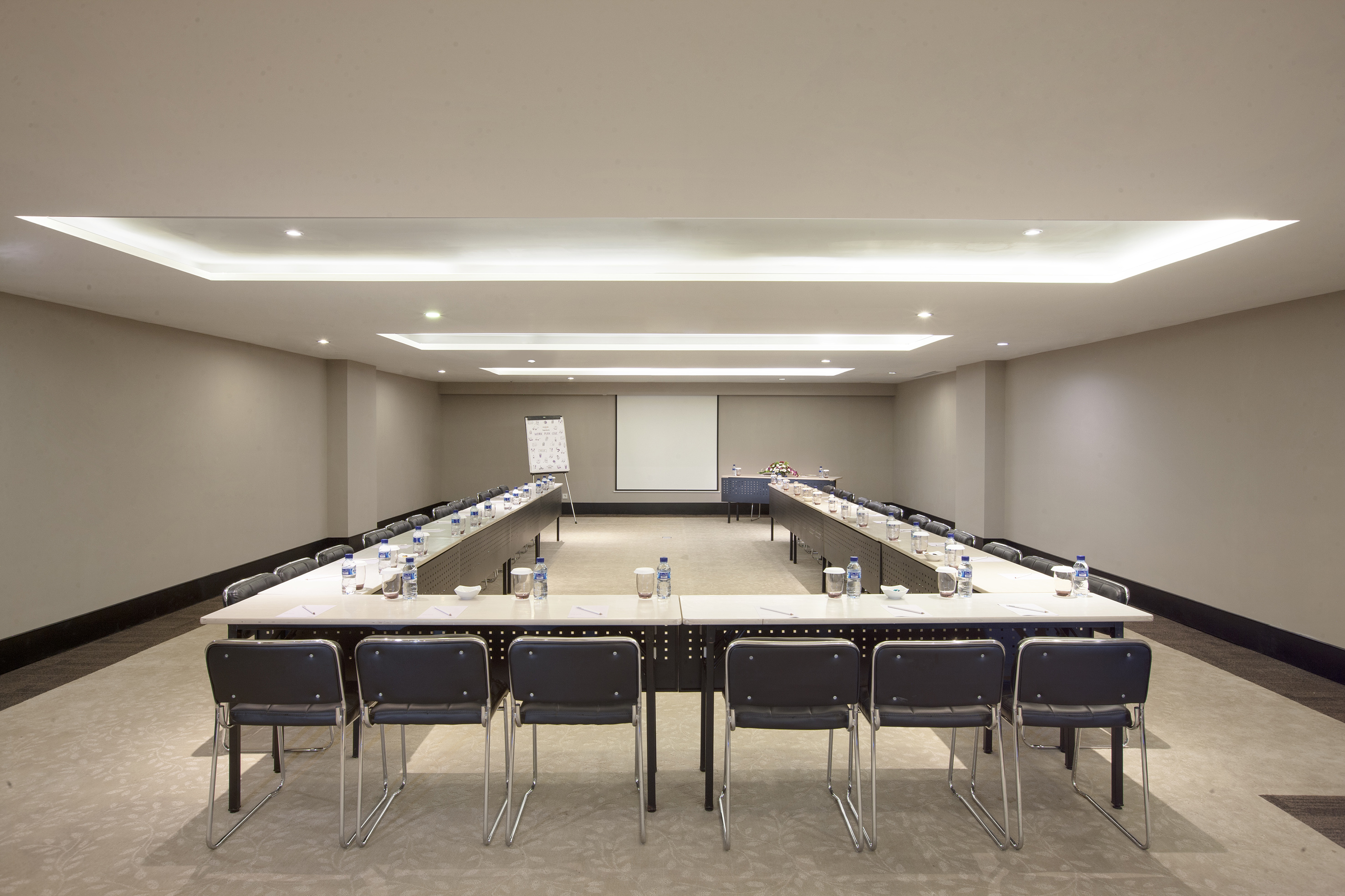 U-shaped meeting room setup with projector screen and whiteboard.
