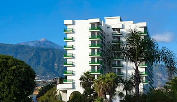 a white building with green balconies and trees