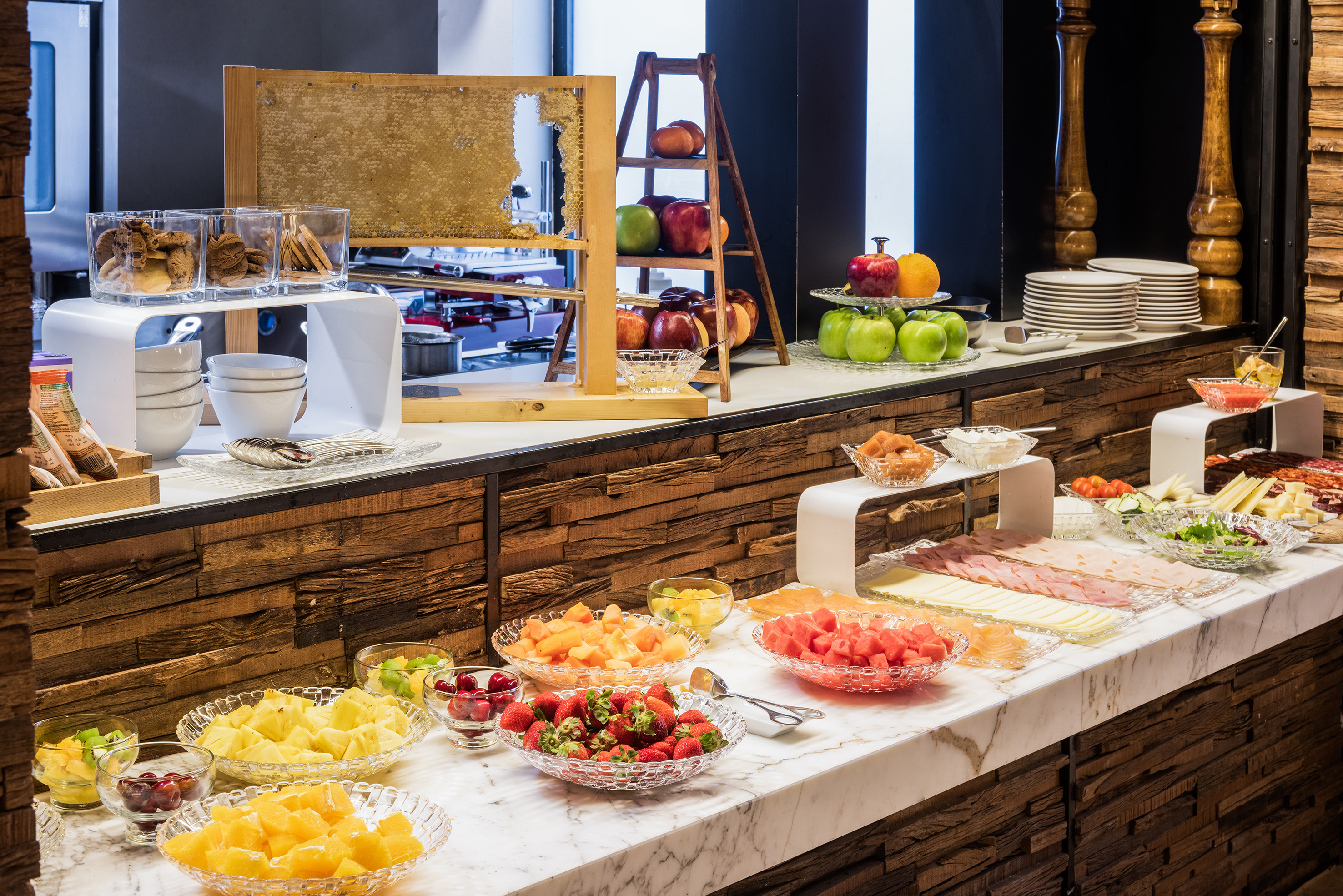 Hotel breakfast buffet with fresh fruit, honeycomb, cookies, meats, and cheese.