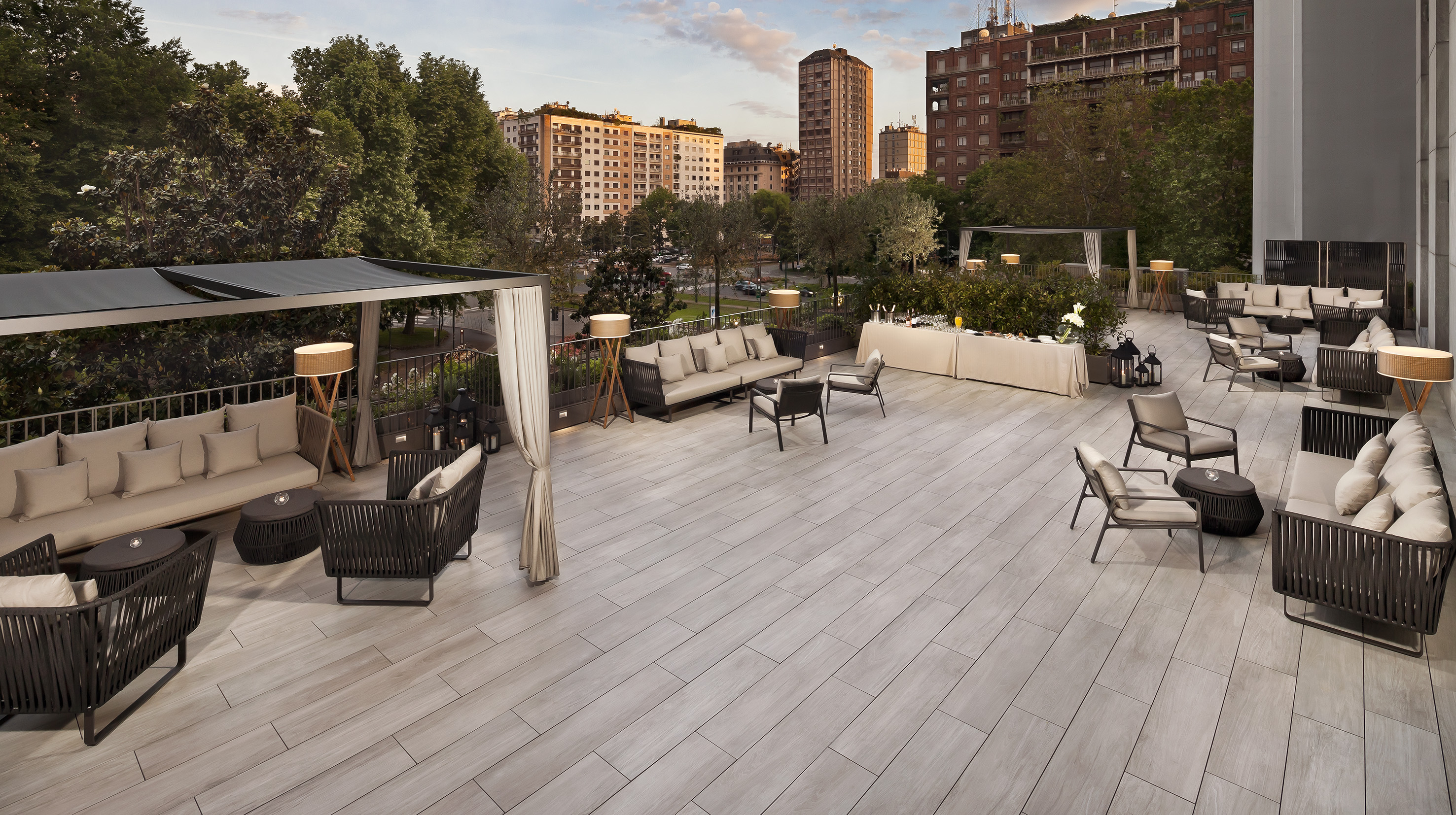 Outdoor hotel terrace with modern lounge furniture, city view, and bar.