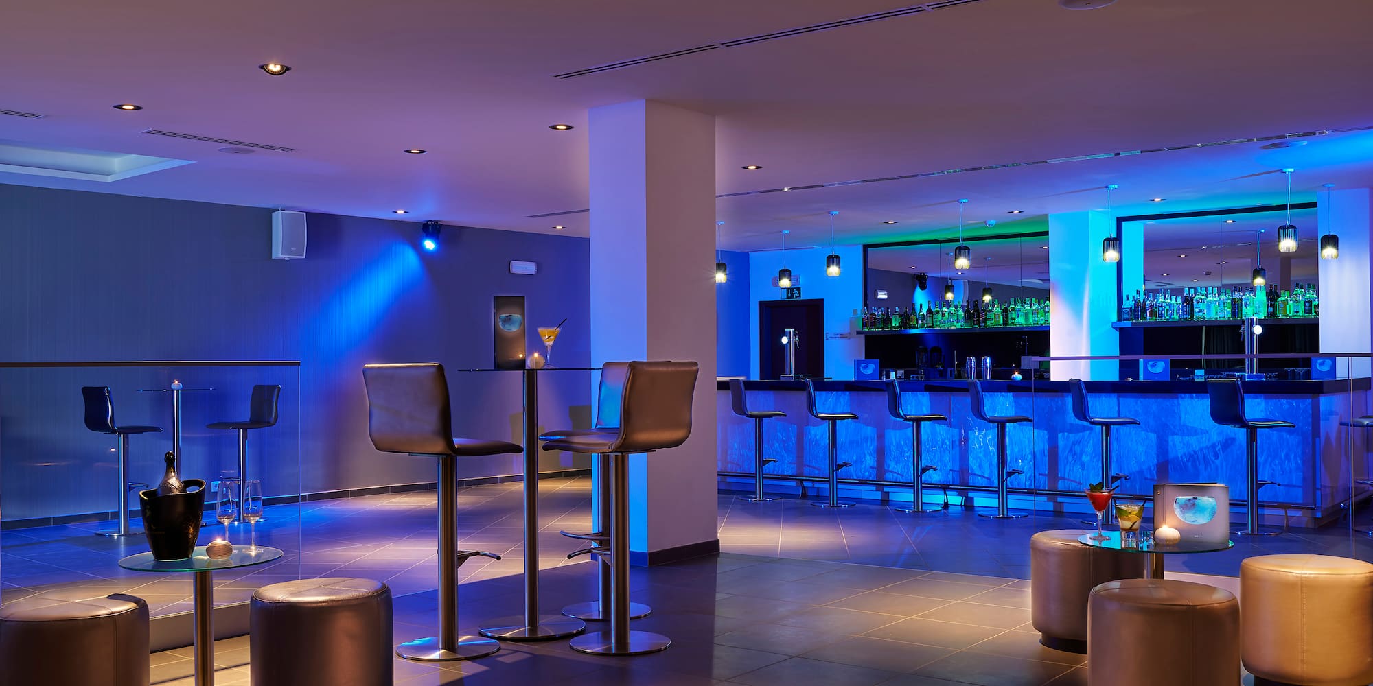 a bar with stools and drinks