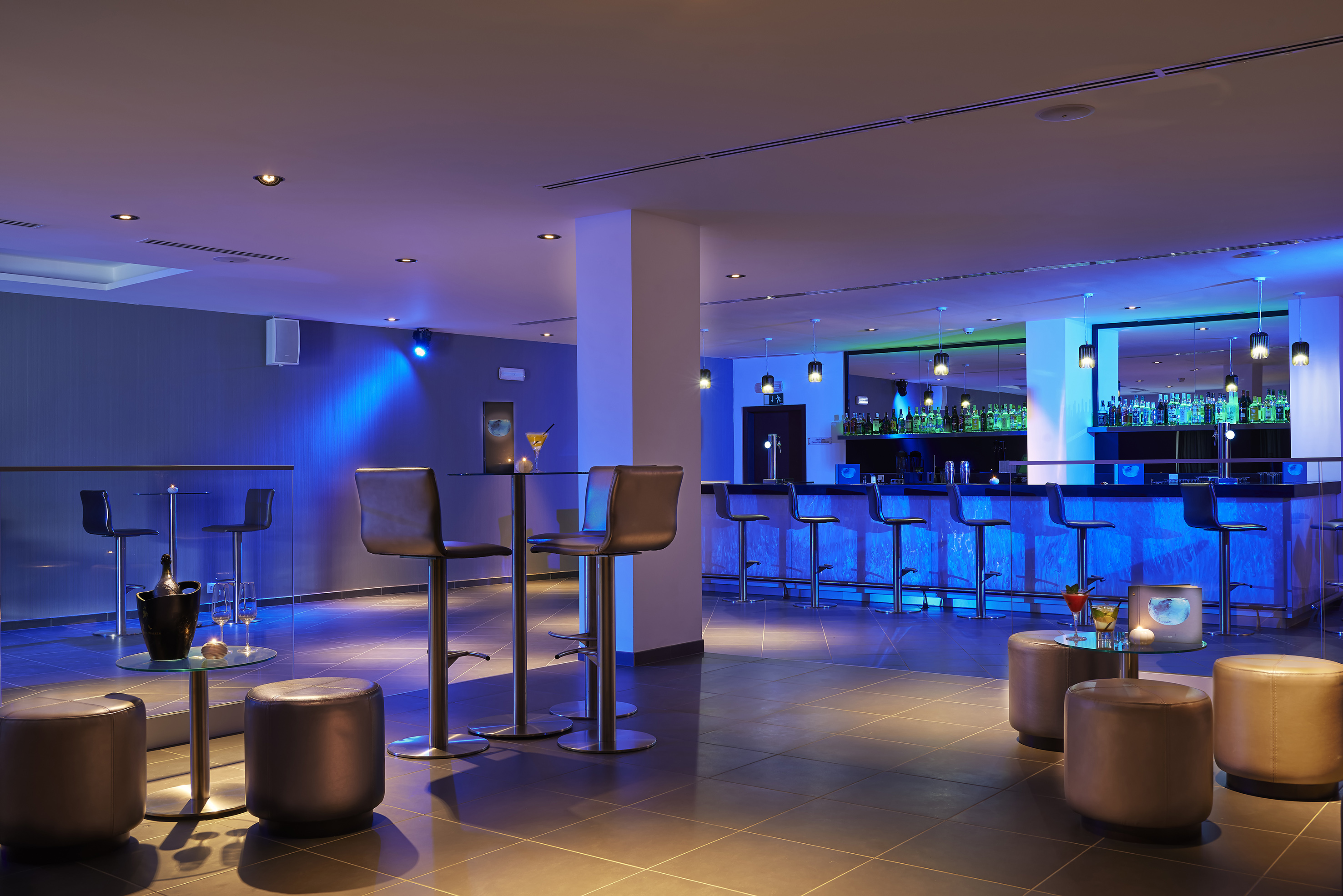 a bar with stools and drinks