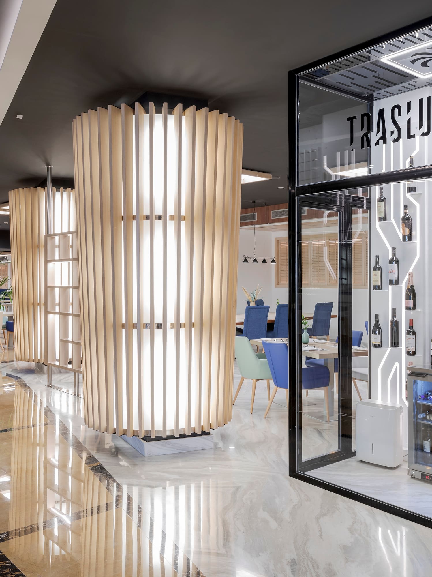 a room with a glass wall and shelves of wine bottles