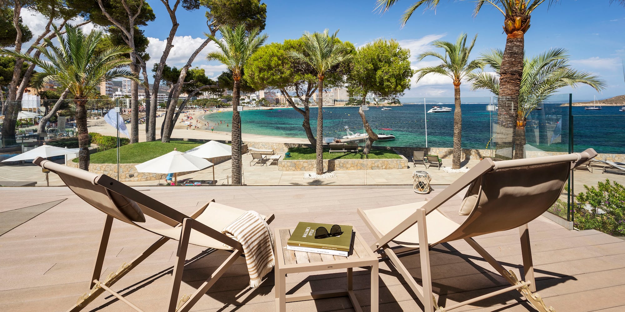 chairs on a deck with palm trees and a beach