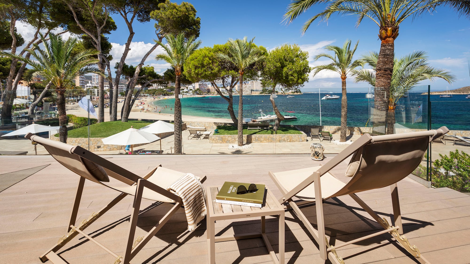 chairs on a deck with palm trees and a beach