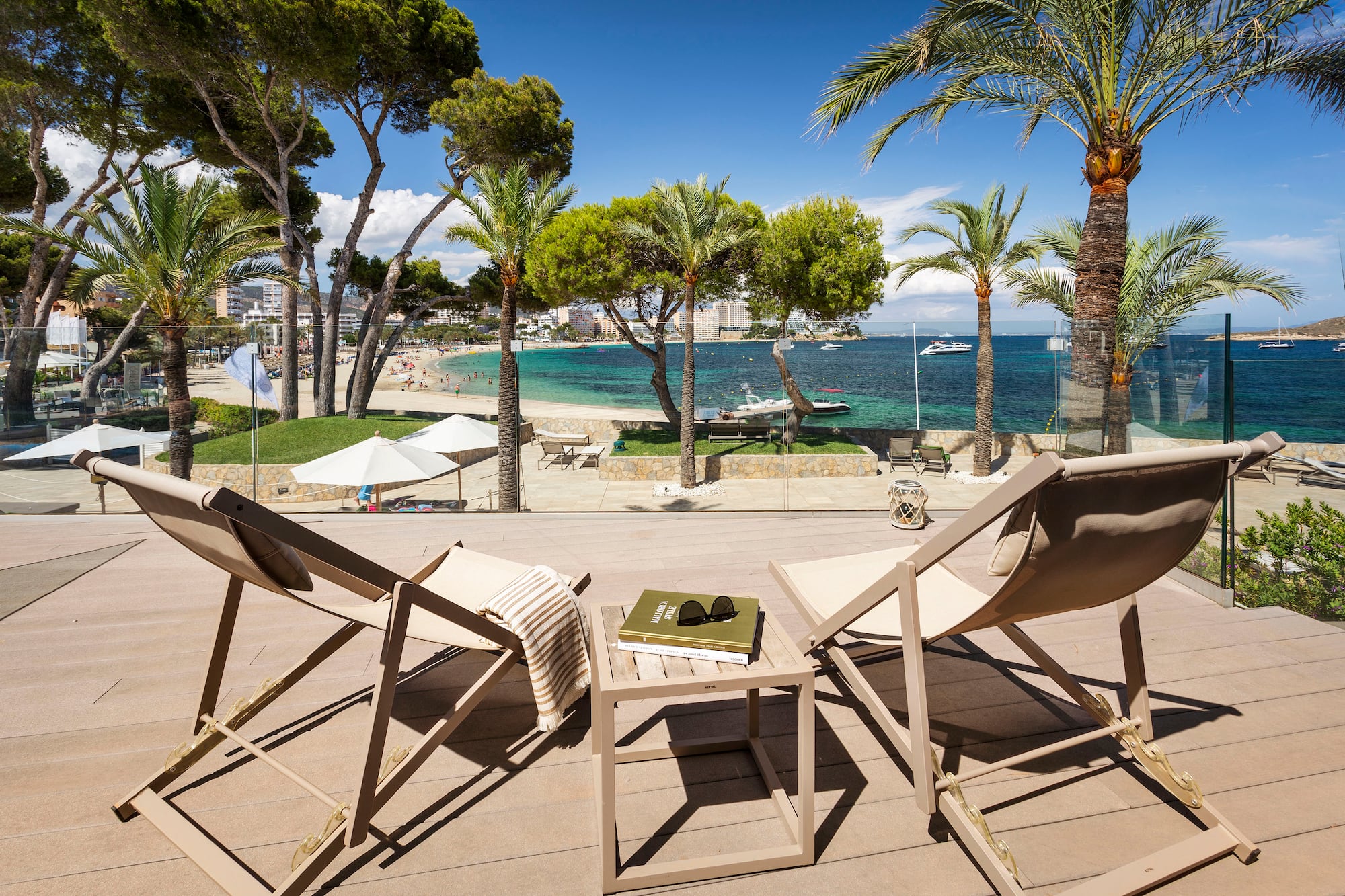 chairs on a deck with palm trees and a beach