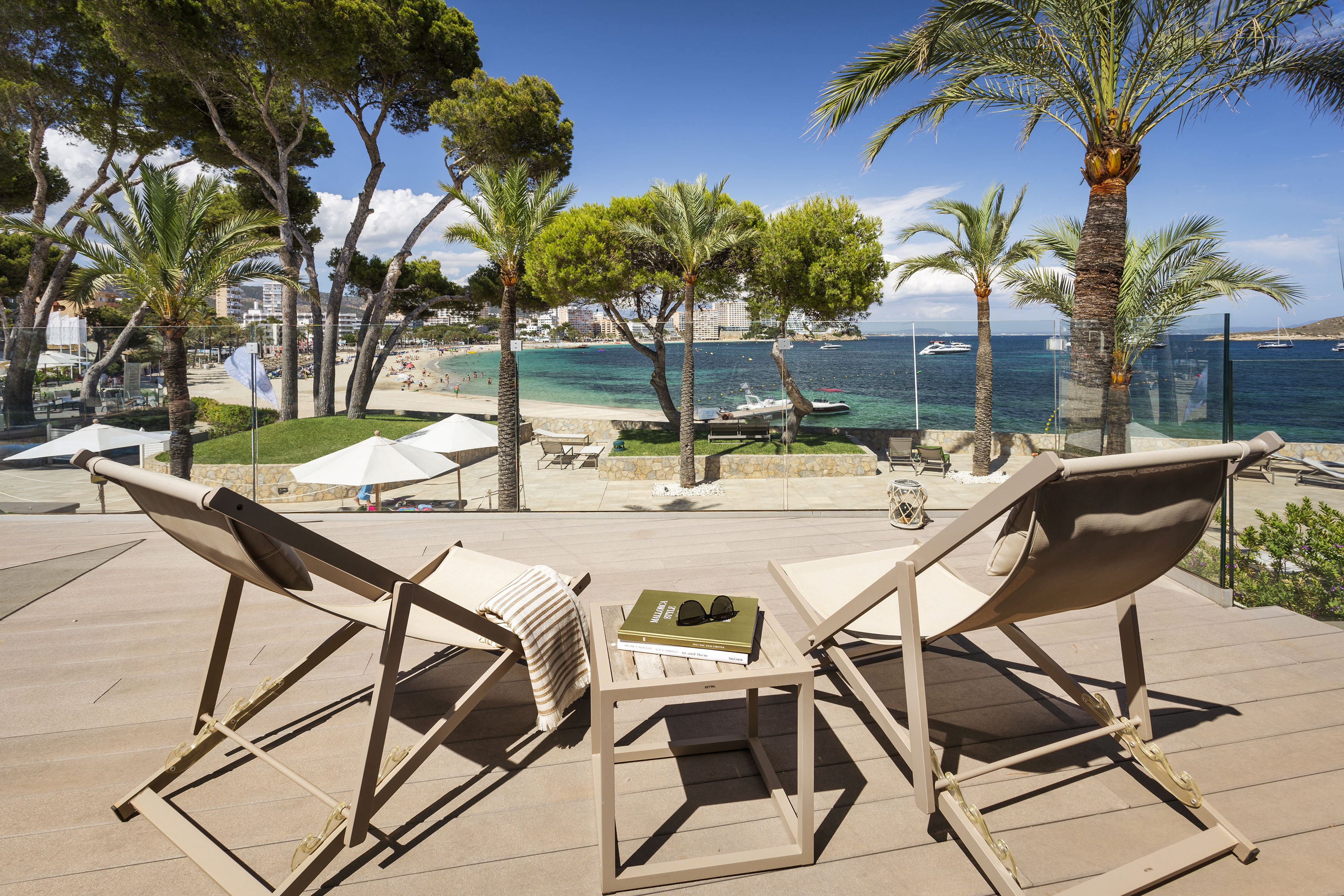 chairs on a deck with palm trees and a beach
