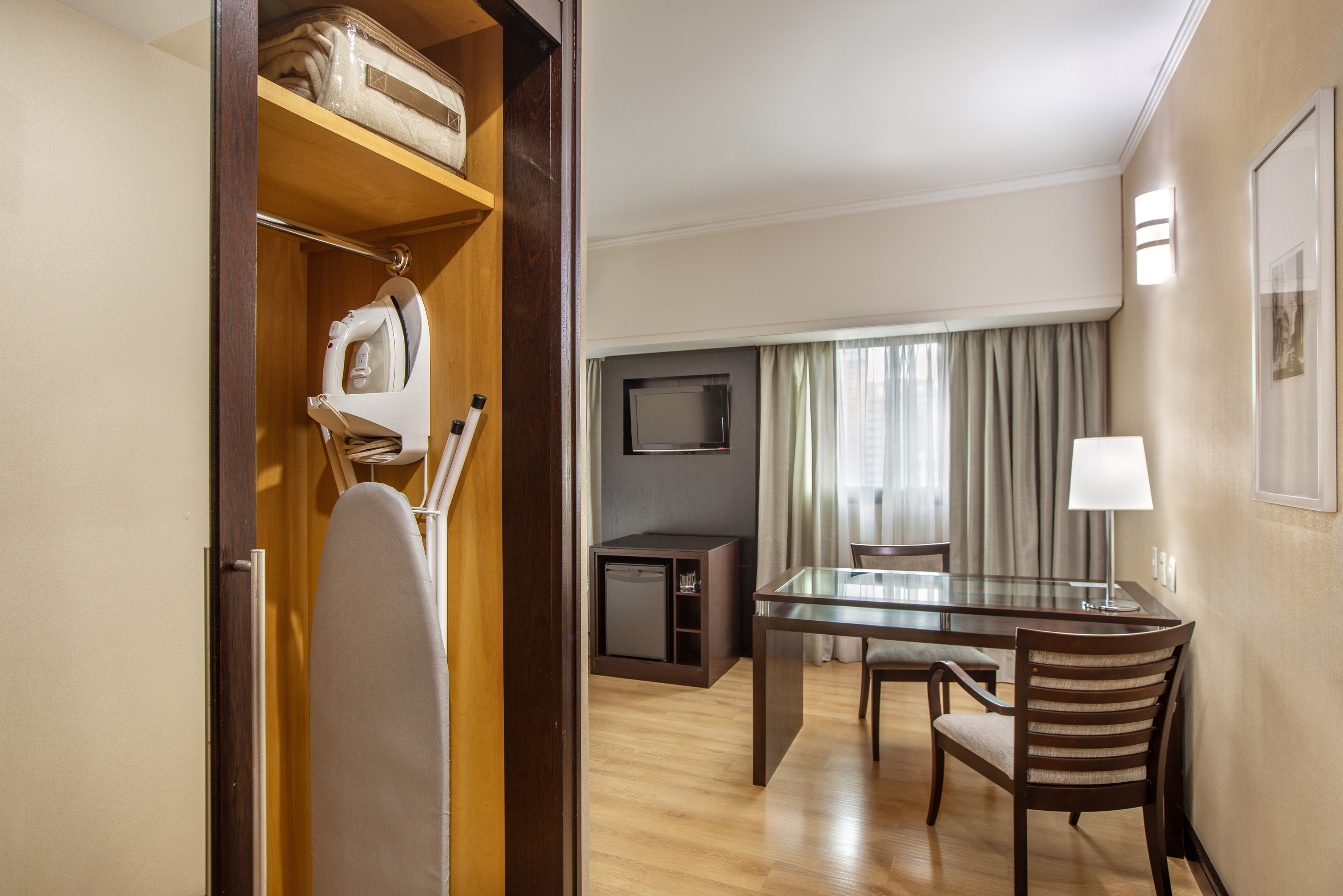 Hotel room with iron, ironing board, work desk, TV, and minibar.