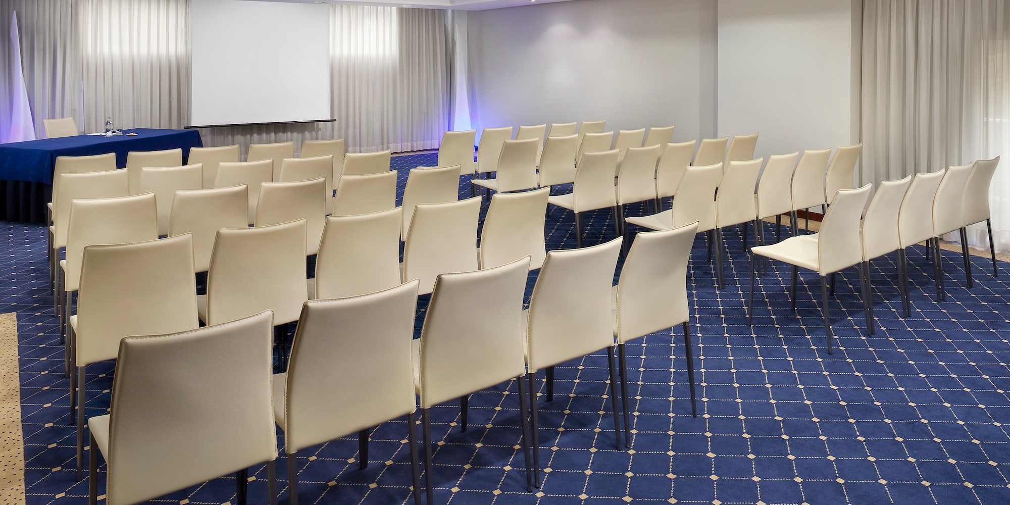 a room with white chairs and blue carpet