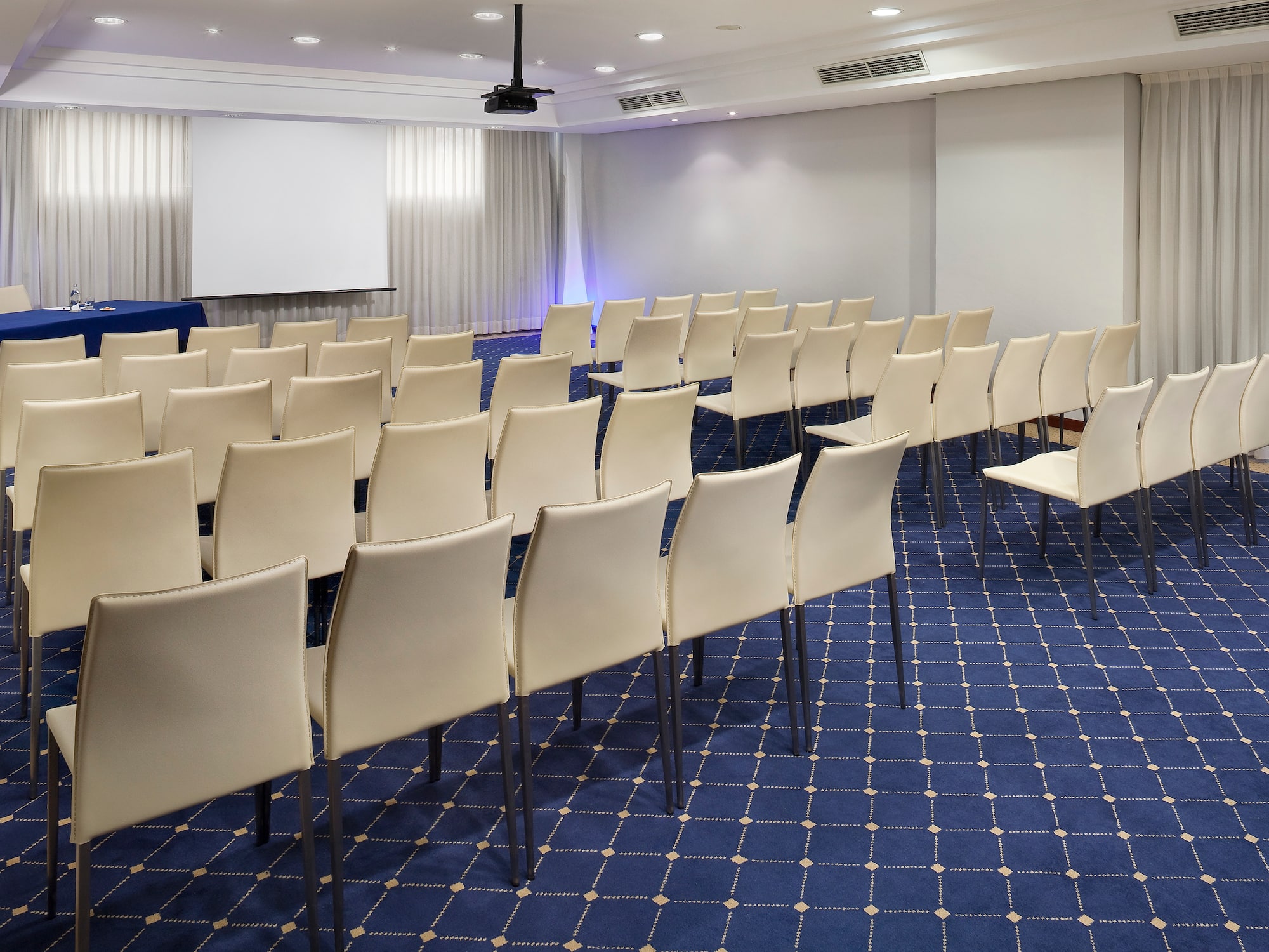 a room with white chairs and blue carpet
