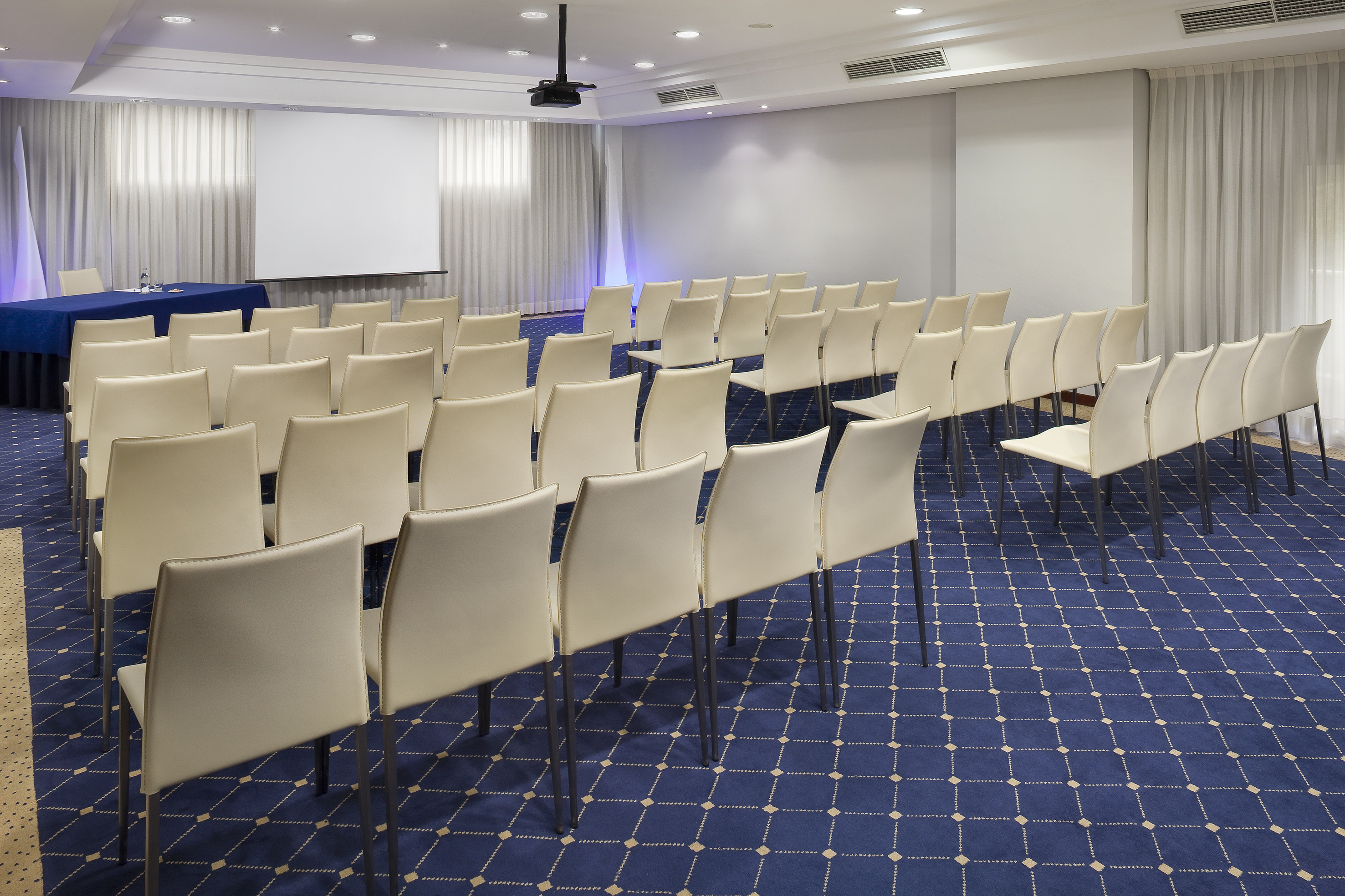 a room with white chairs and blue carpet