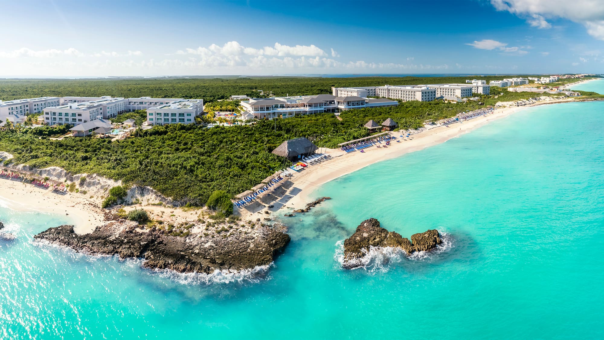 a beach with a group of buildings and a body of water