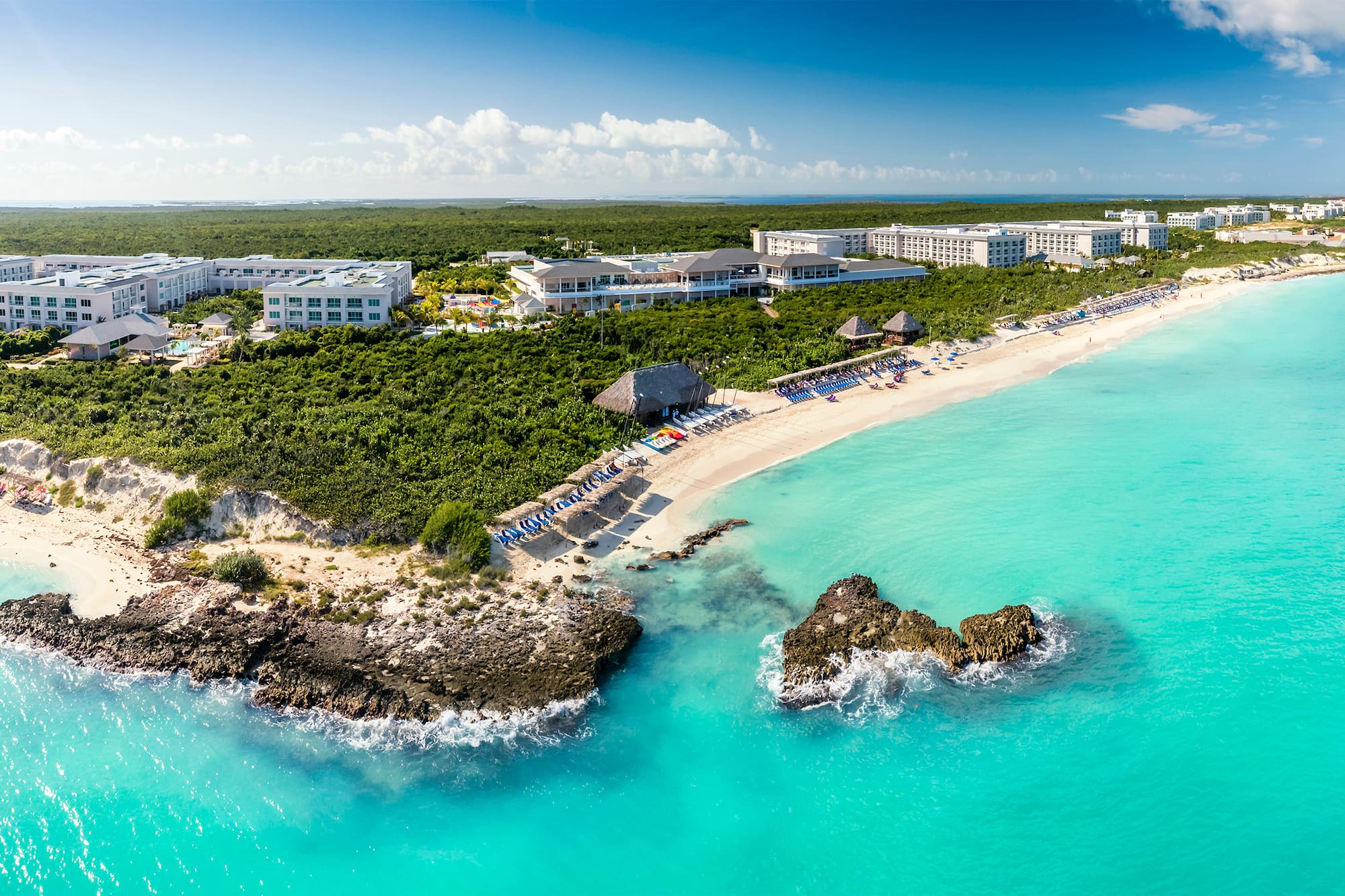 a beach with a group of buildings and a body of water