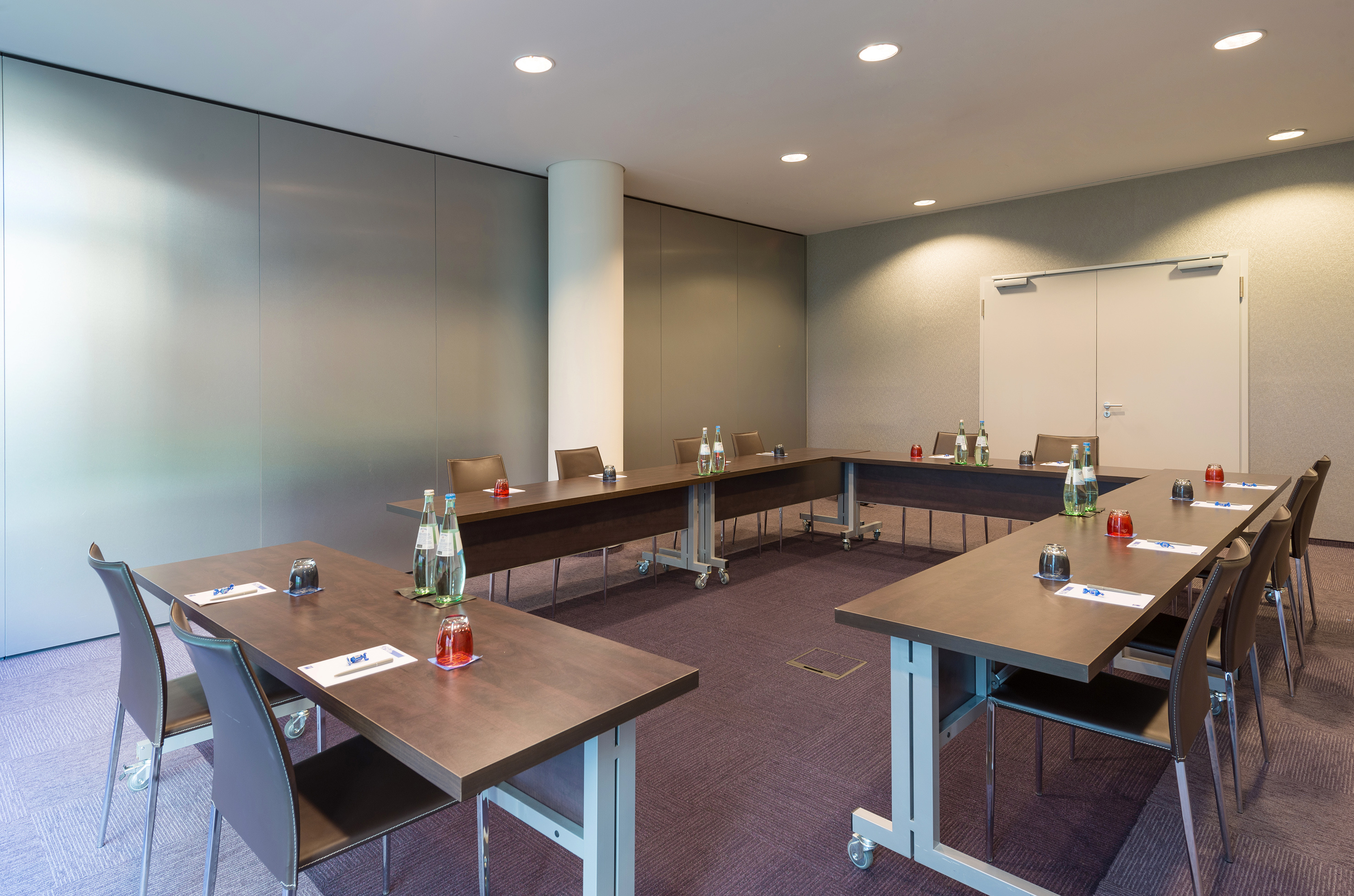 U-shape conference room setup with tables, chairs, and water bottles for meetings.