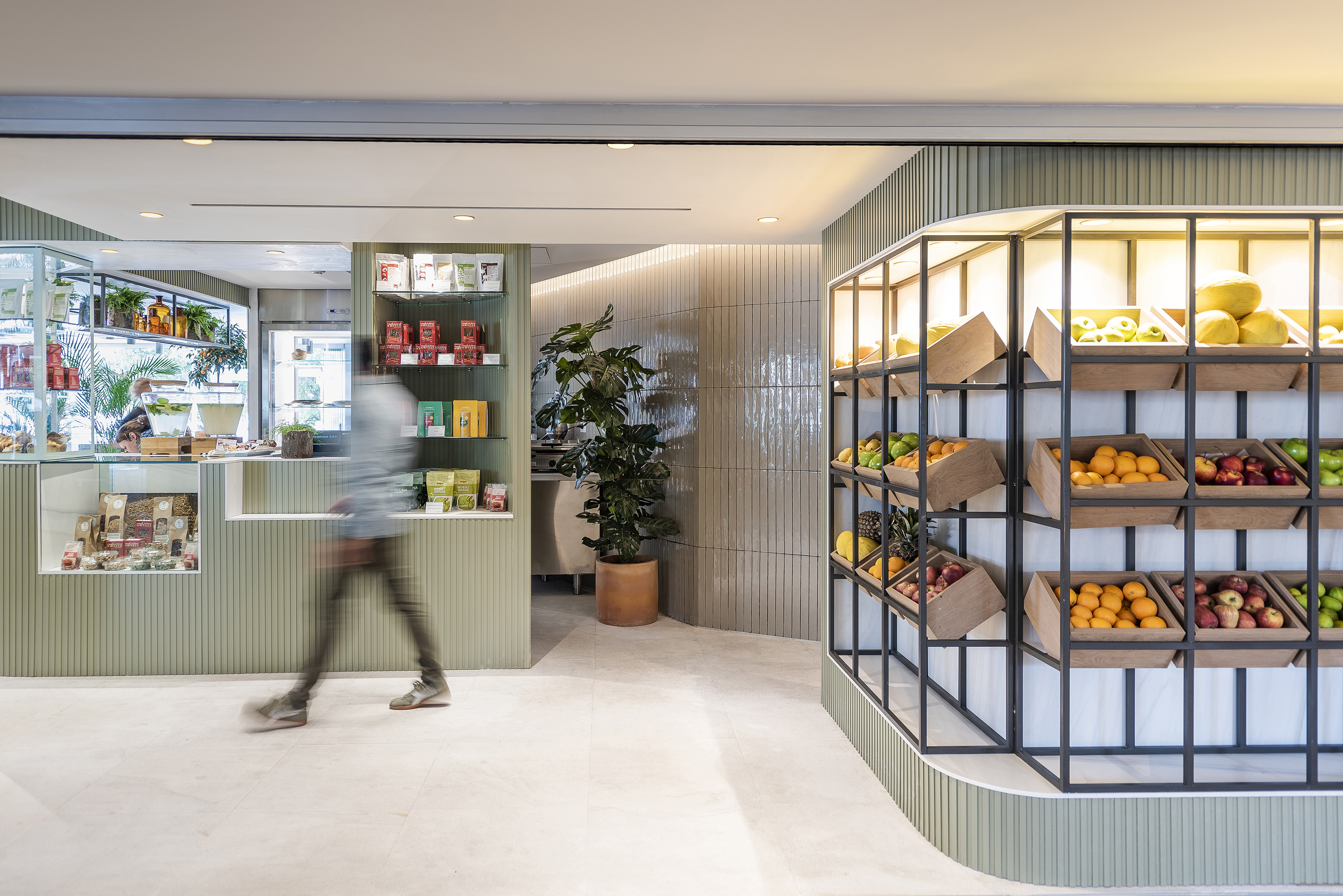Modern market interior with vibrant fresh fruit display and green walls.