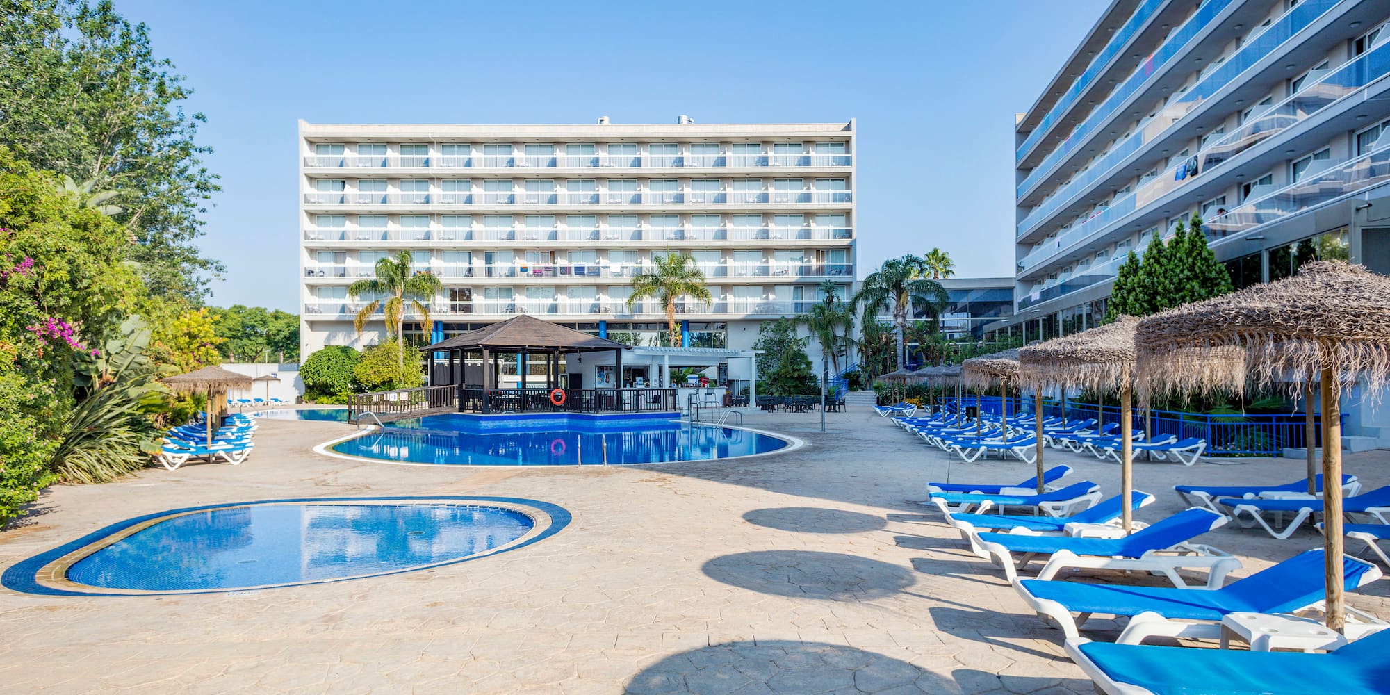 a pool with lounge chairs and umbrellas in front of a building