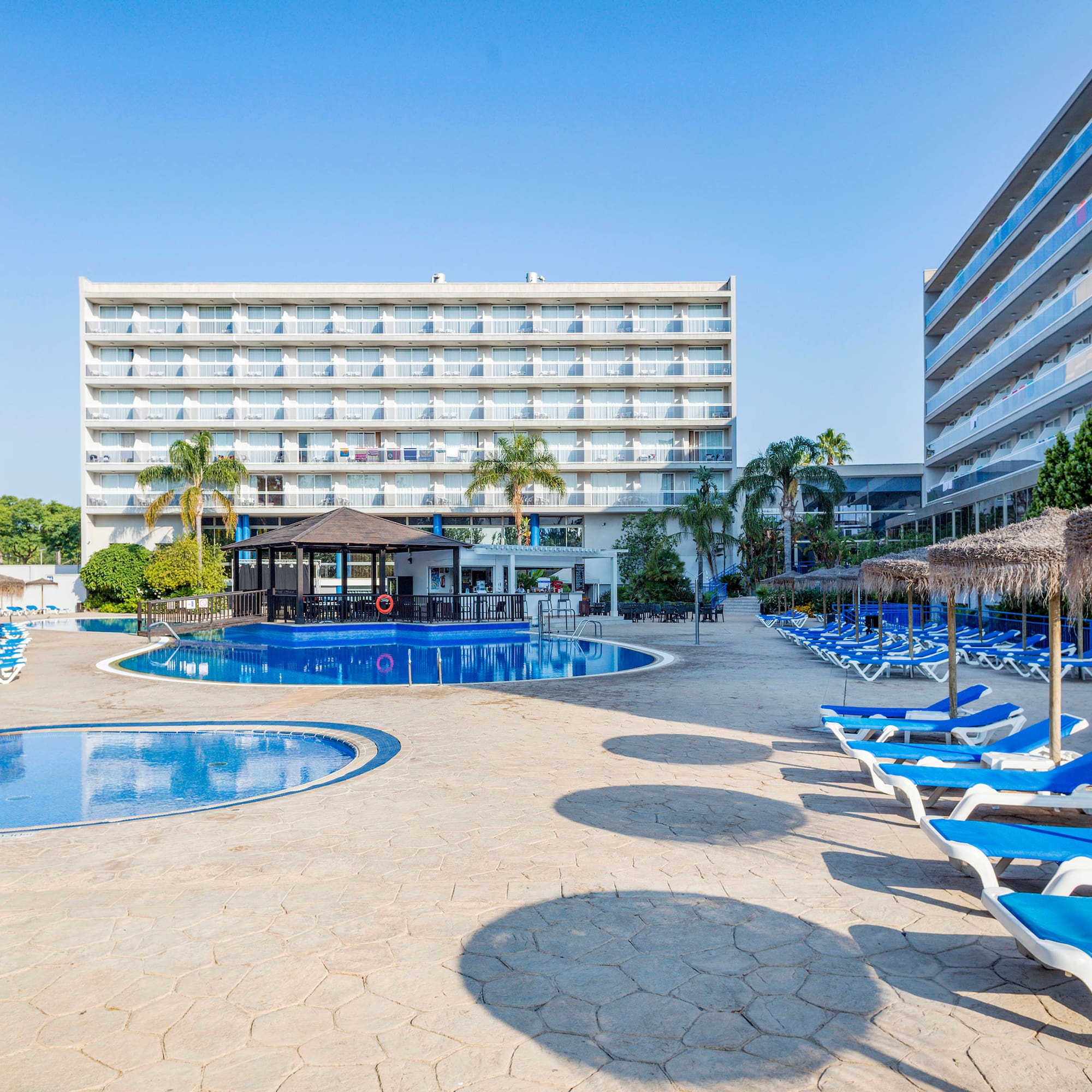 a pool with lounge chairs and umbrellas in front of a building