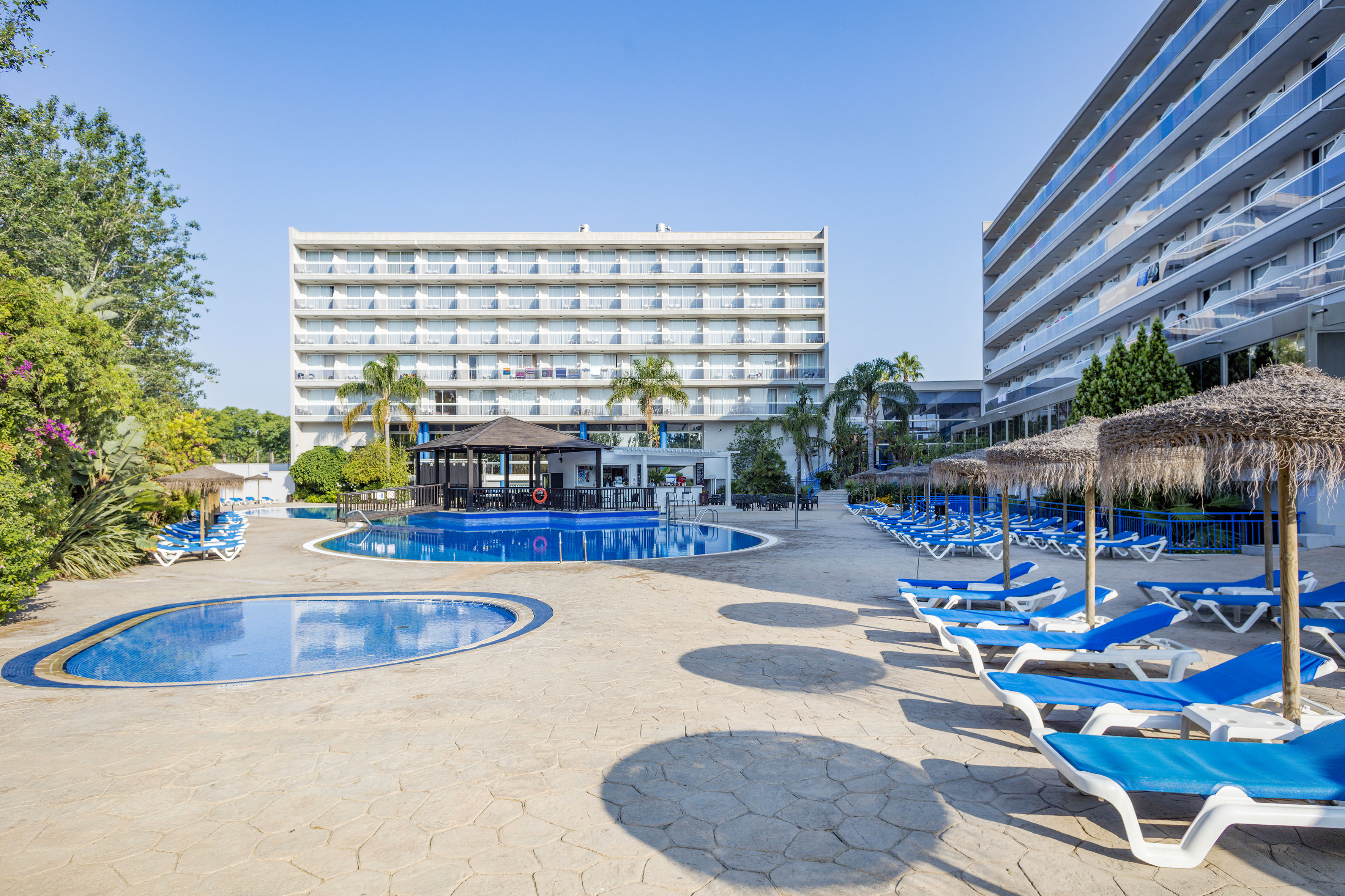 a pool with lounge chairs and umbrellas in front of a building