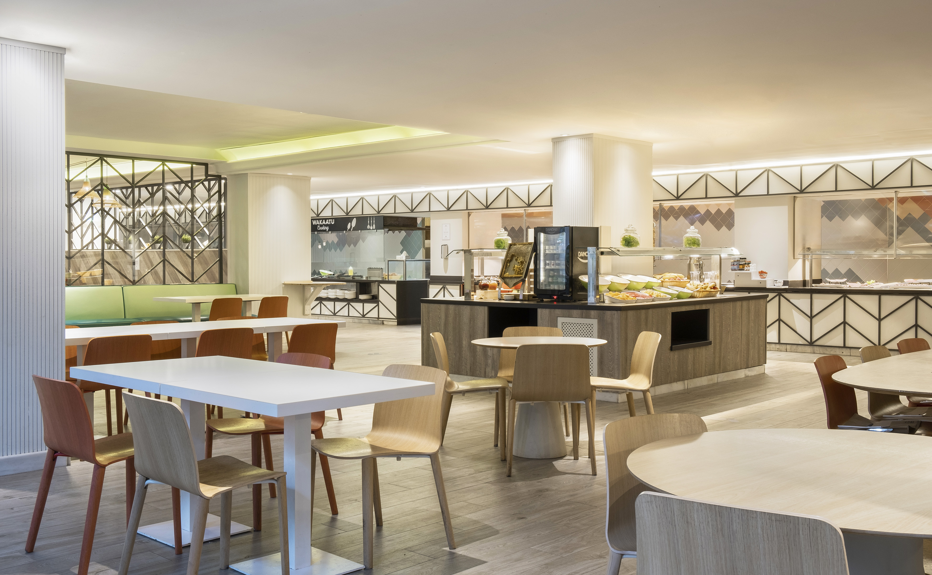 Modern hotel buffet dining area with tables, chairs, and food counters.