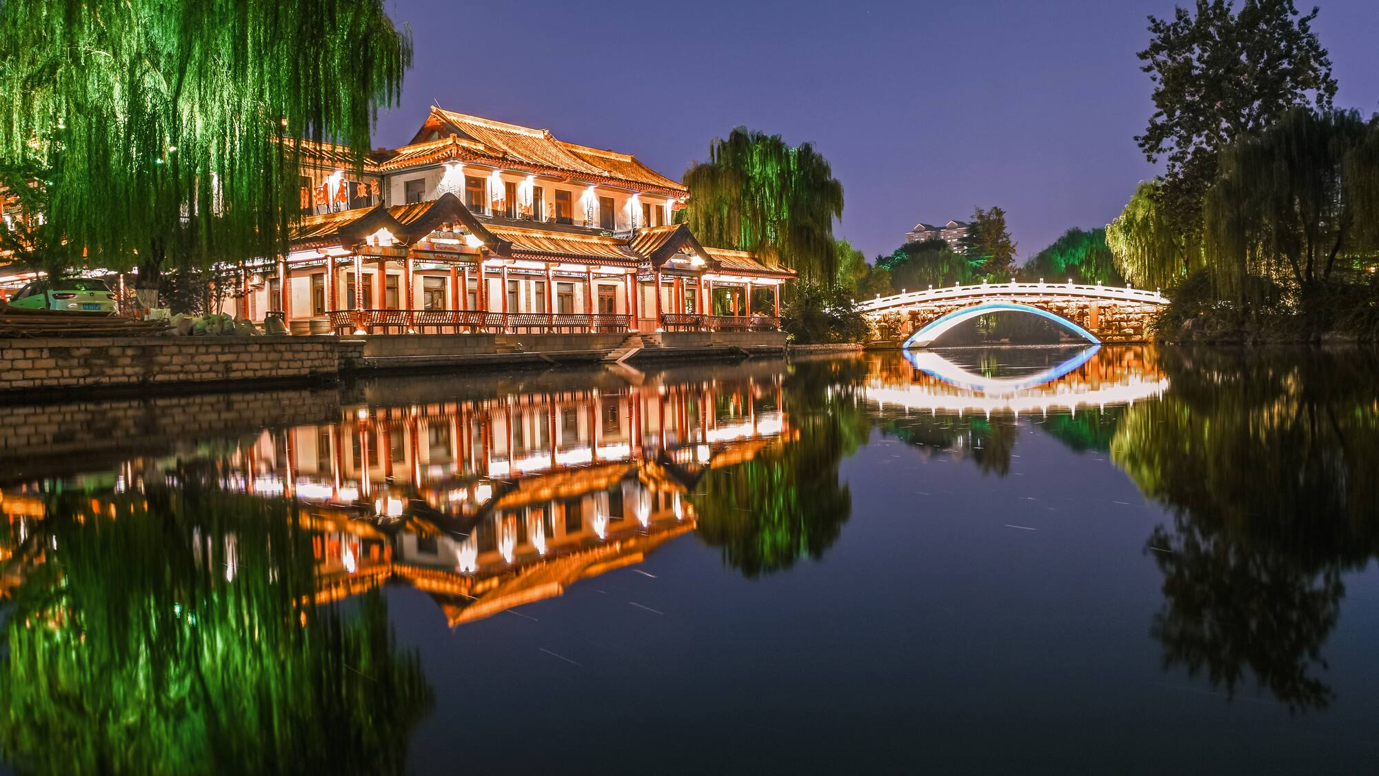 a building with lights on it and a bridge over water