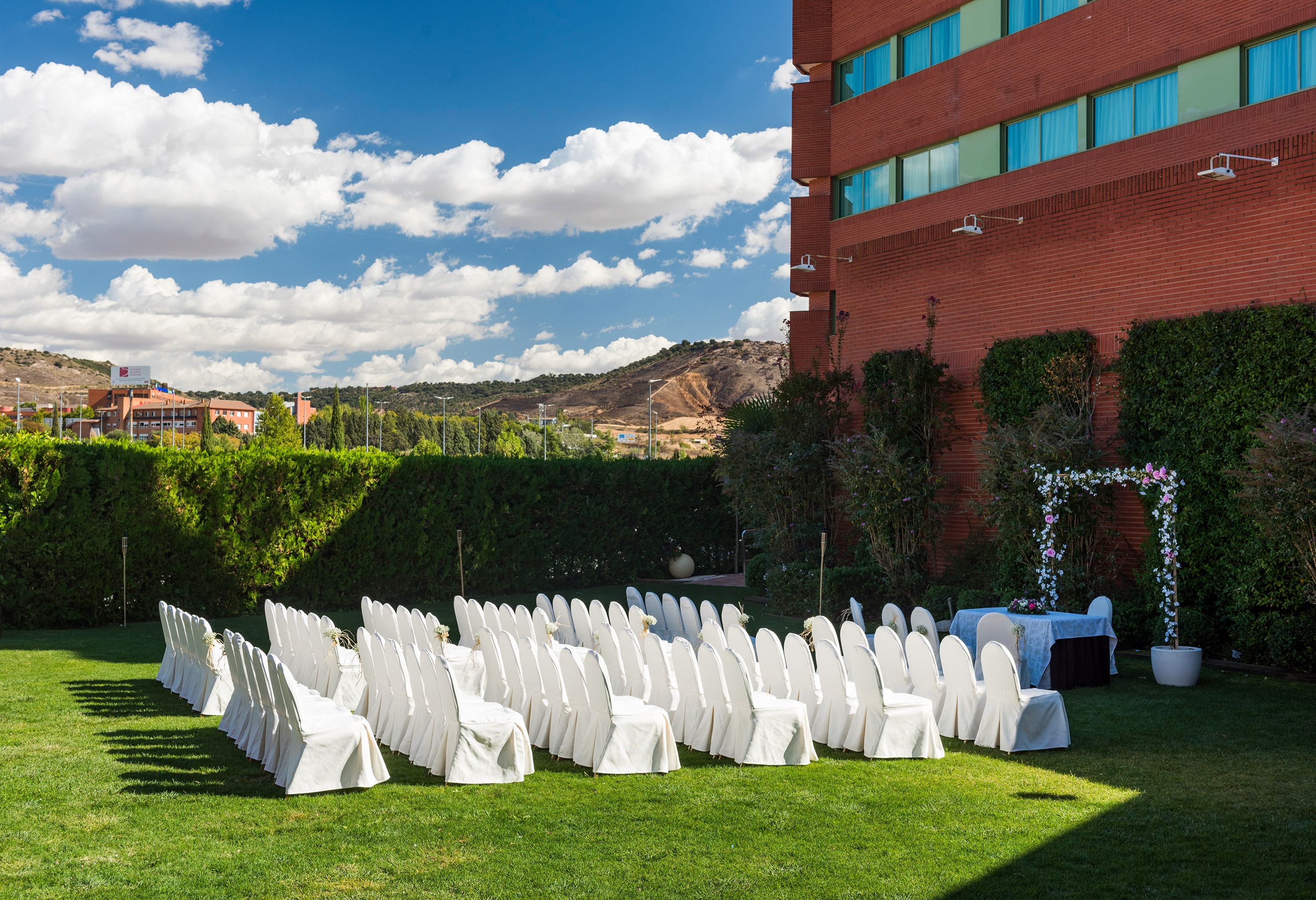White chairs on green lawn for outdoor wedding ceremony at a hotel venue.