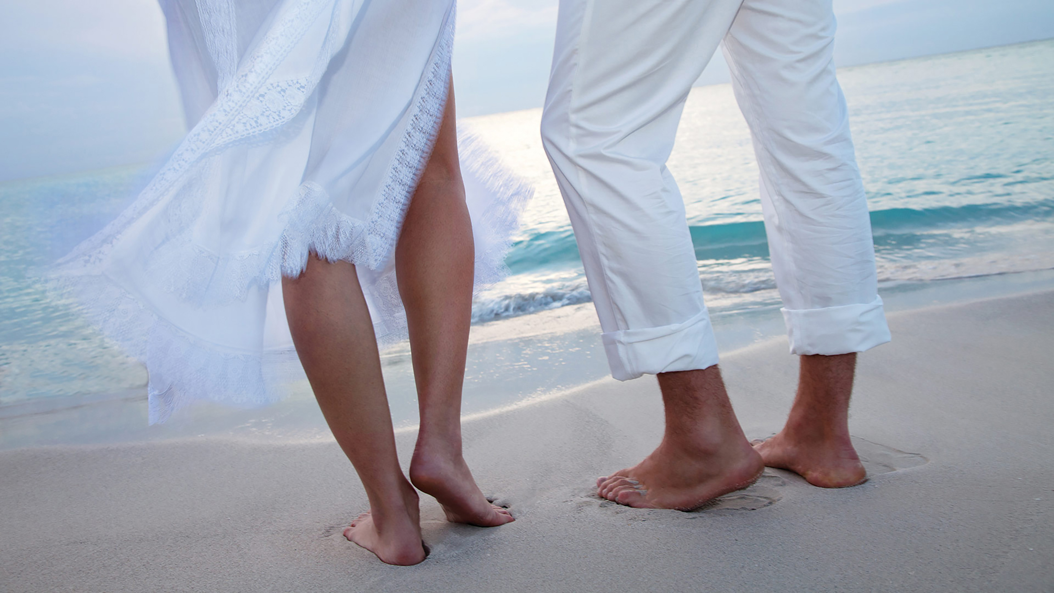 a close up of two people's feet on a beach