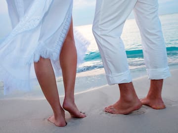 a close up of two people's feet on a beach