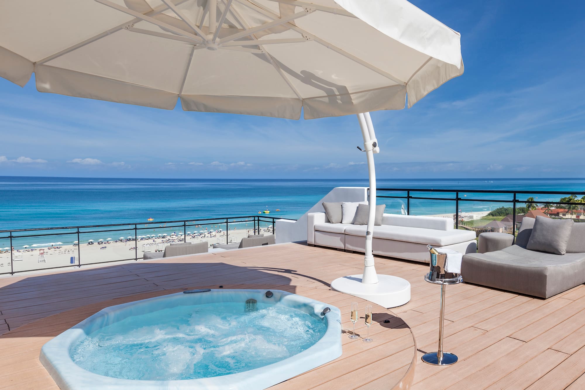a hot tub on a deck with a beach and water in the background