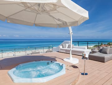 a hot tub on a deck with a beach and water in the background