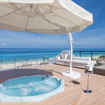 a hot tub on a deck with a beach and water in the background