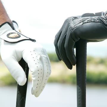 a pair of hands wearing gloves holding a golf club