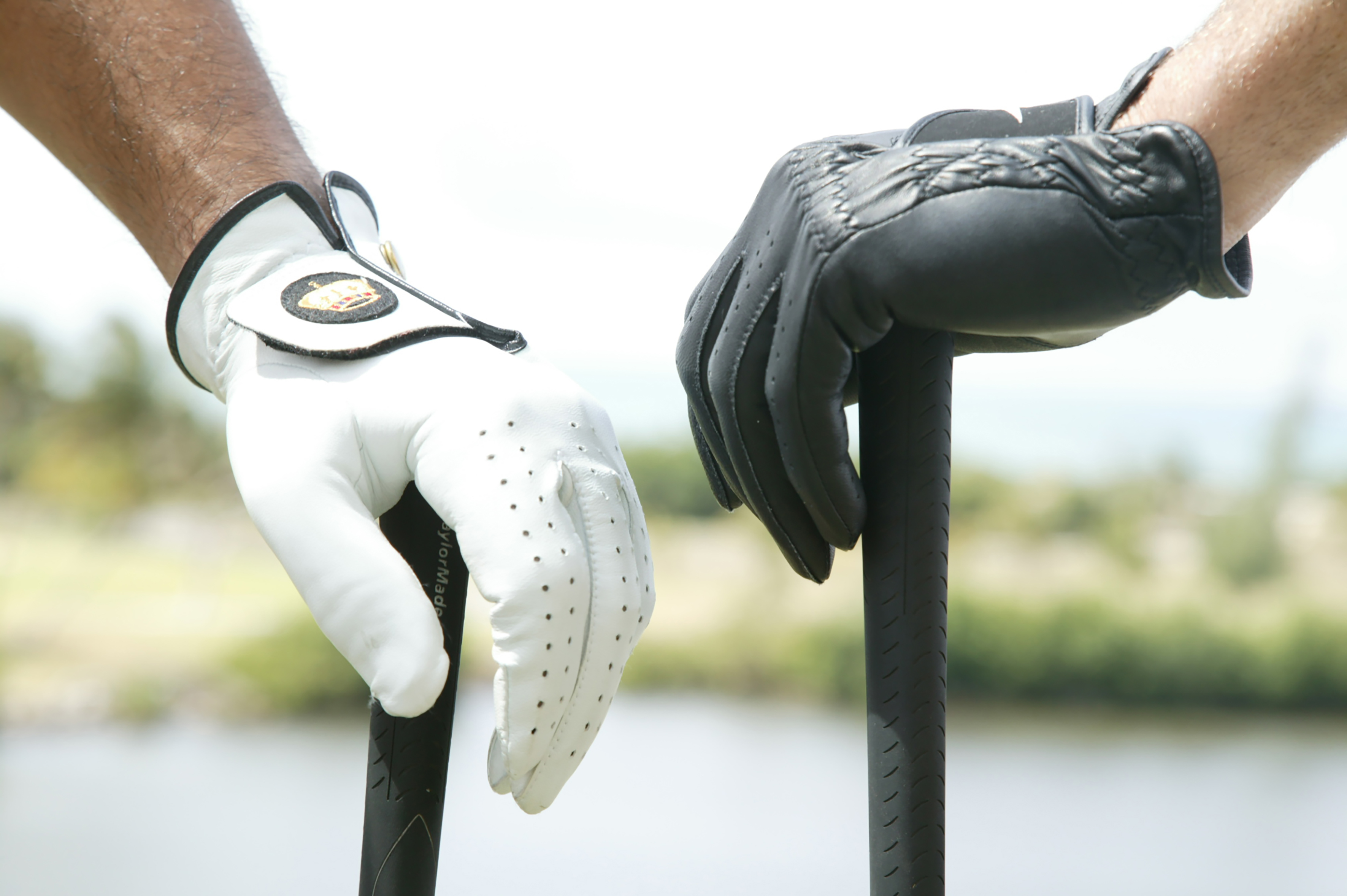 a pair of hands wearing gloves holding a golf club