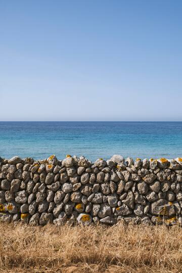 a stone wall with a body of water in the background