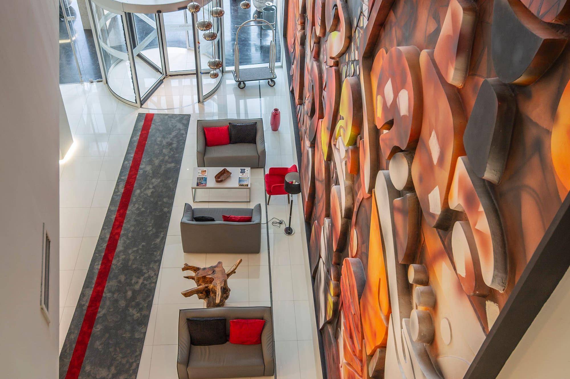 Modern hotel lobby with abstract mural, seating area, and revolving door.