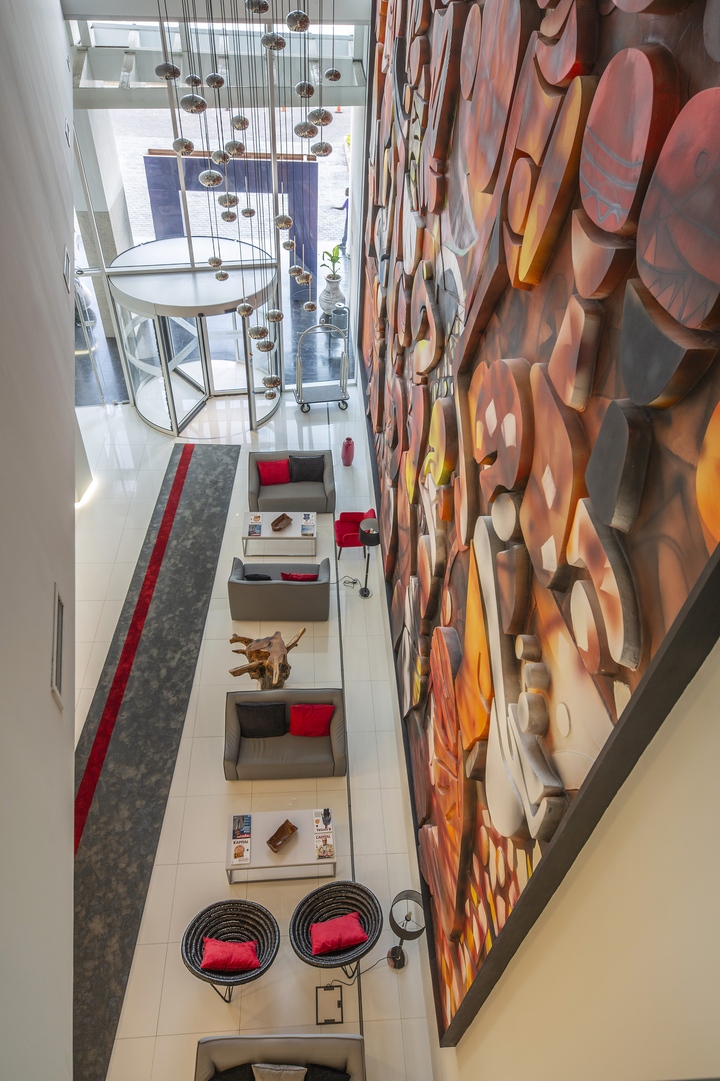 Modern hotel lobby with abstract mural, seating area, and revolving door.