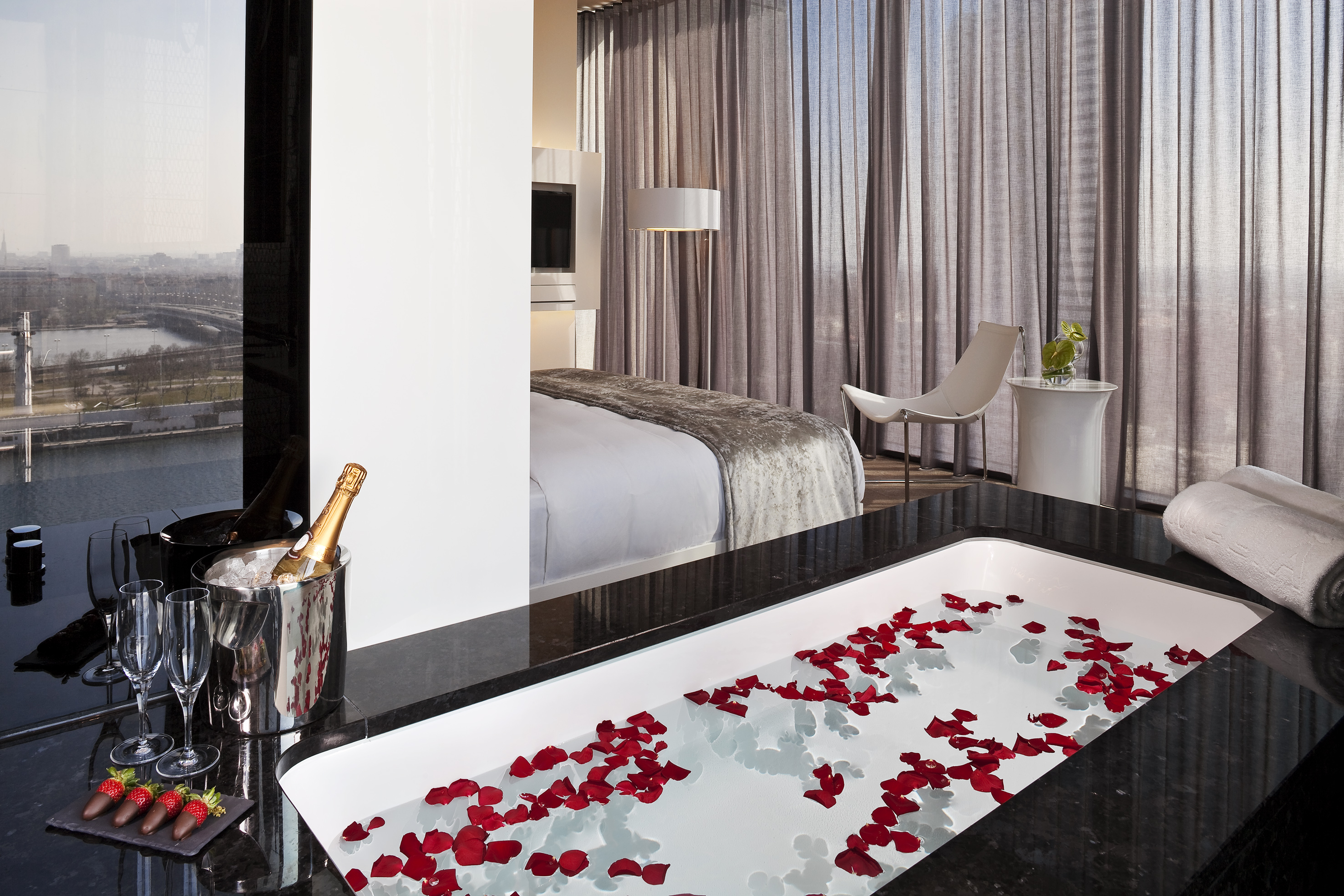 Luxury hotel suite with rose petal bath, champagne, and city view.