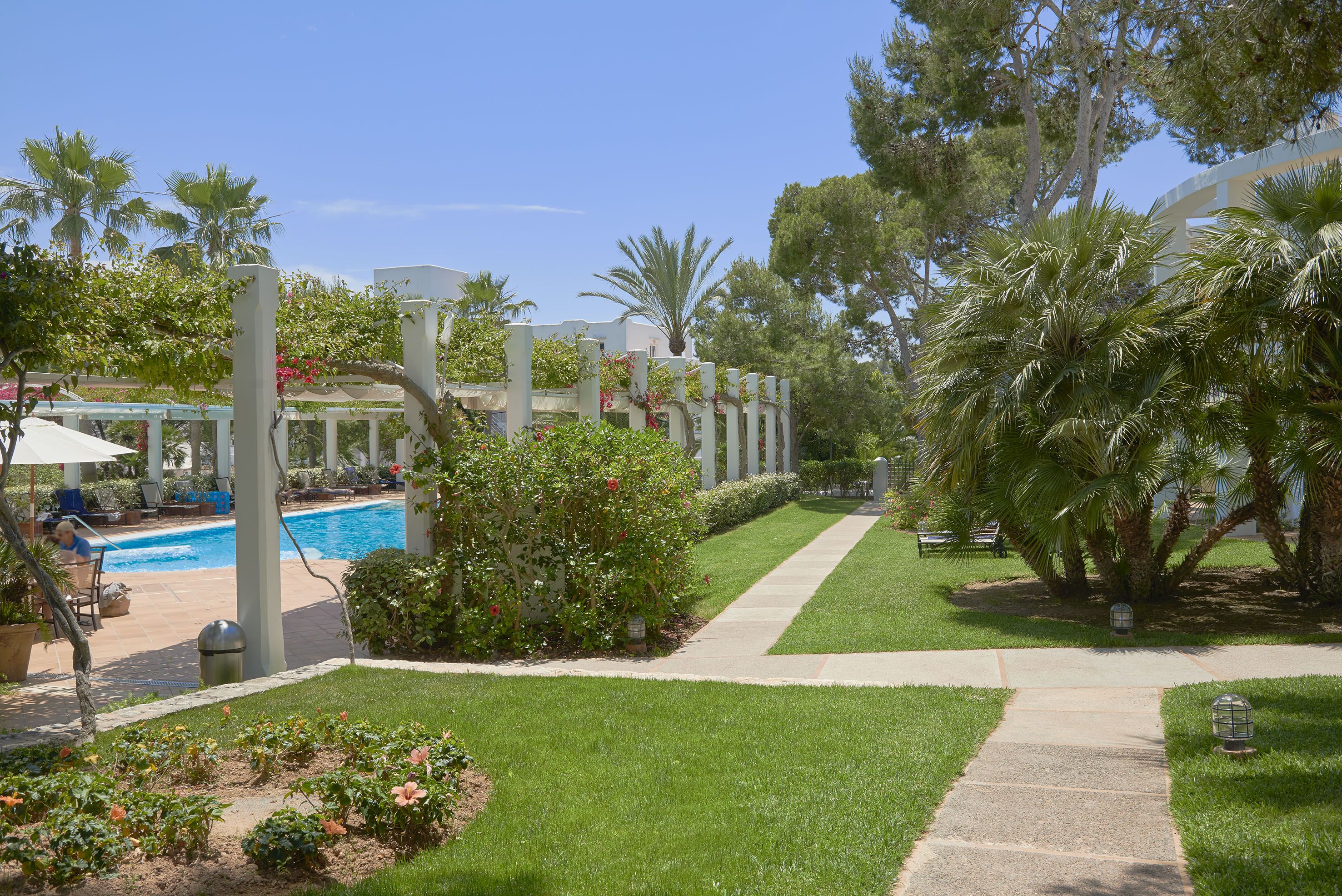 Tropical resort garden with a swimming pool, pergola, and green lawns. - Piscine paesaggistiche sorprendenti - Meliá Cala d'Or Boutique Hotel, Maiorca