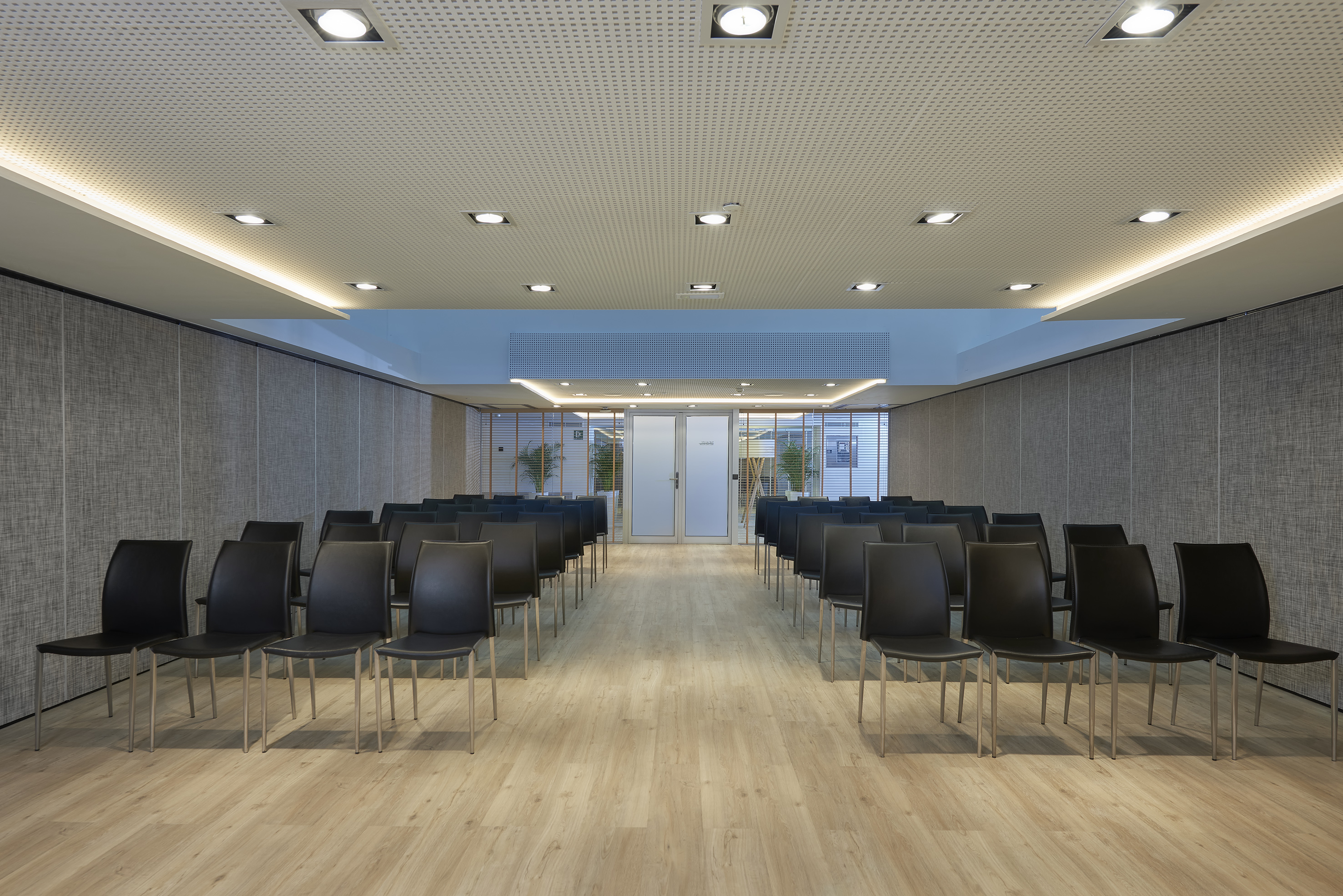 Spacious corporate meeting room with rows of black chairs, recessed lighting.