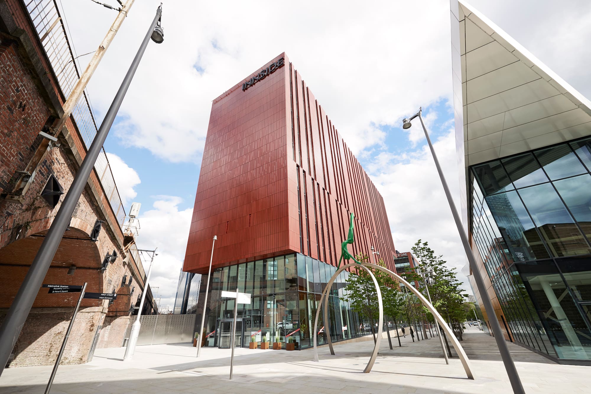 INNSIDE Manchester hotel, modern red building, glass base, old brick archway.