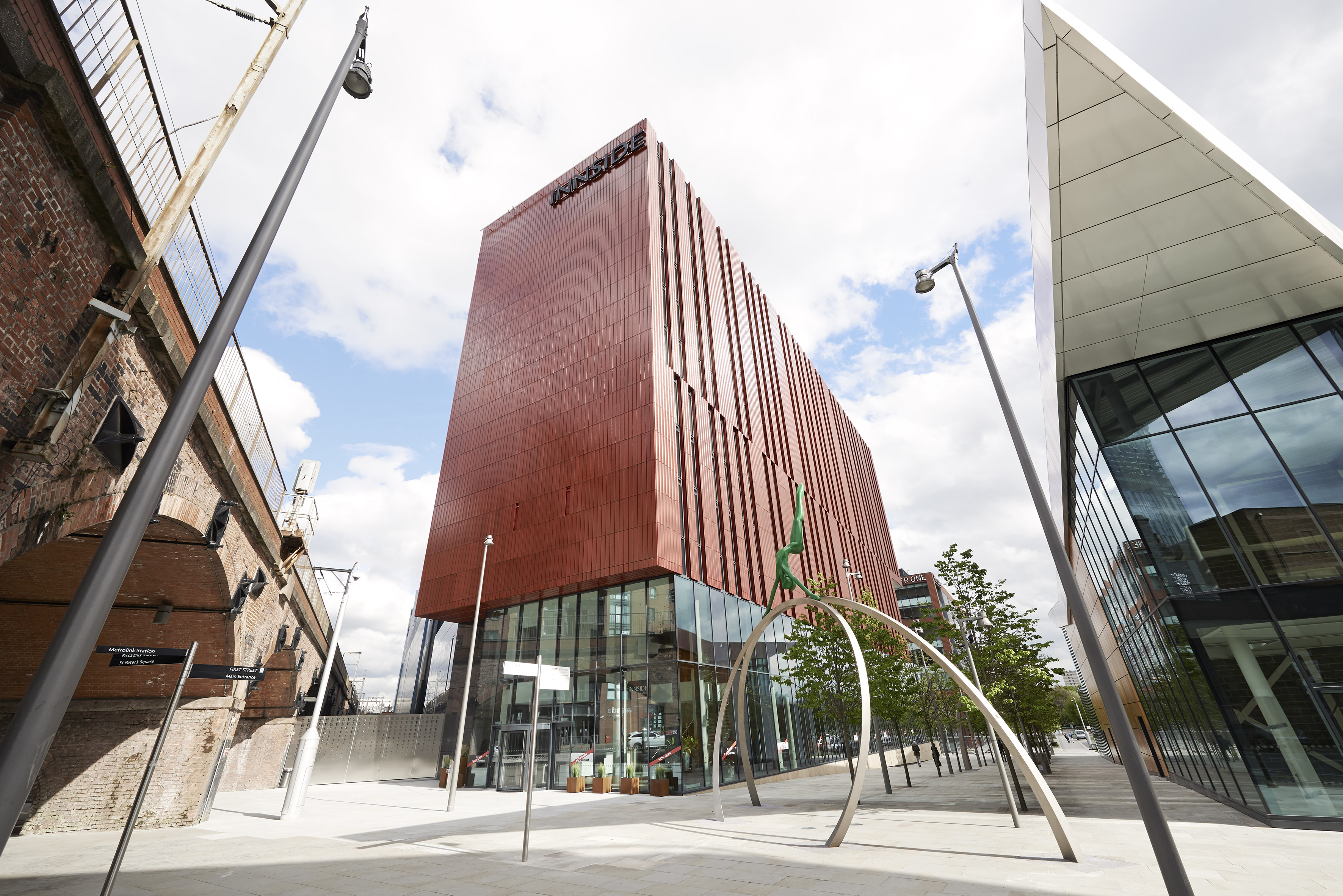 INNSIDE Manchester hotel, modern red building, glass base, old brick archway.