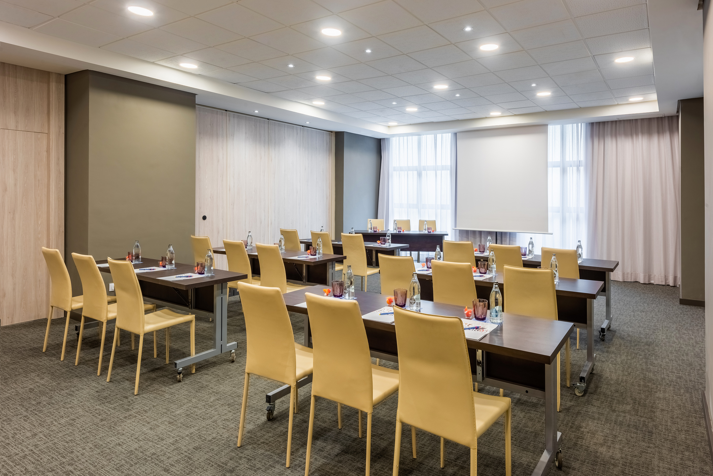 Modern meeting room setup with tables, chairs, and projector screen.