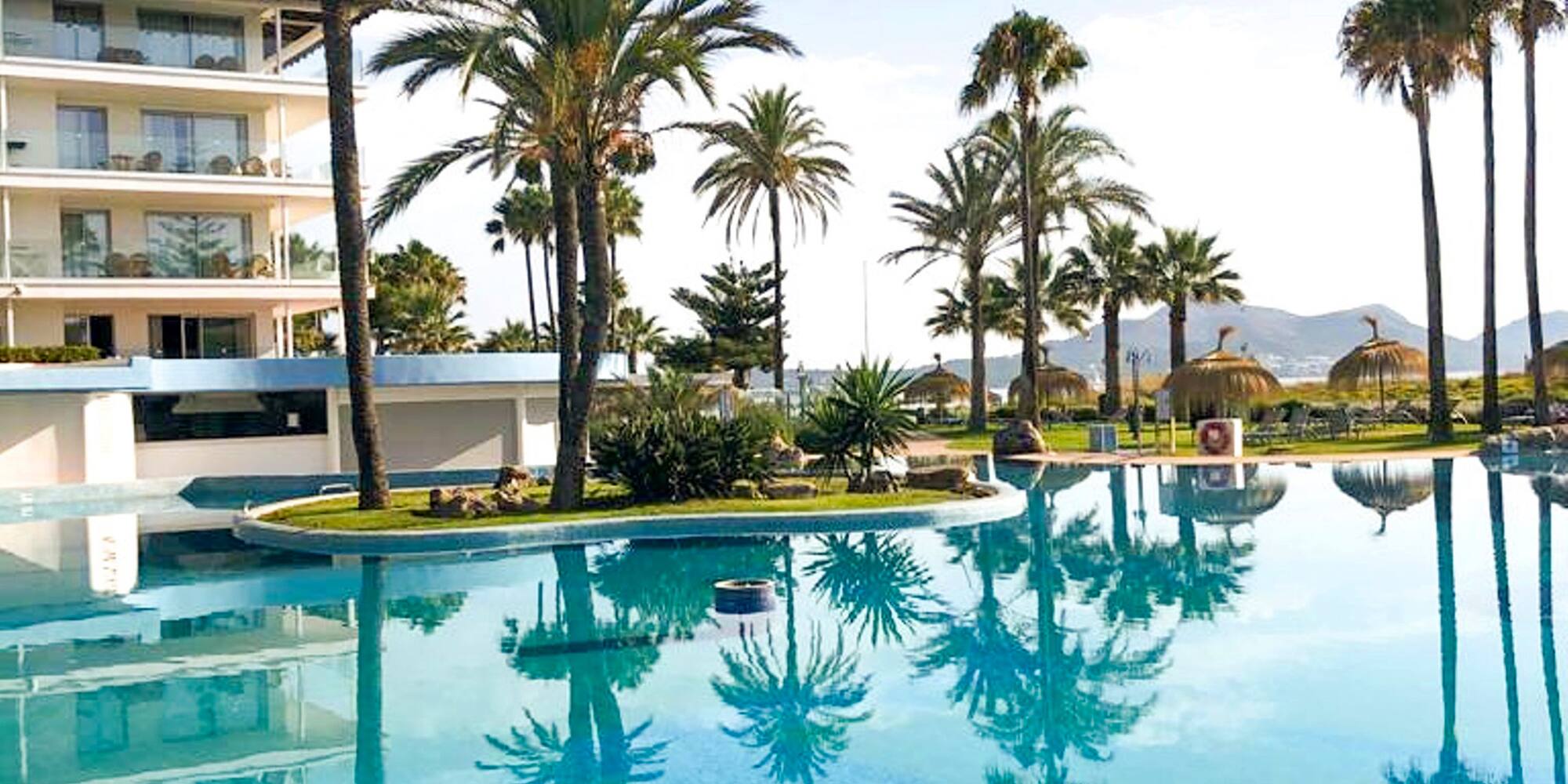 a pool with palm trees and buildings