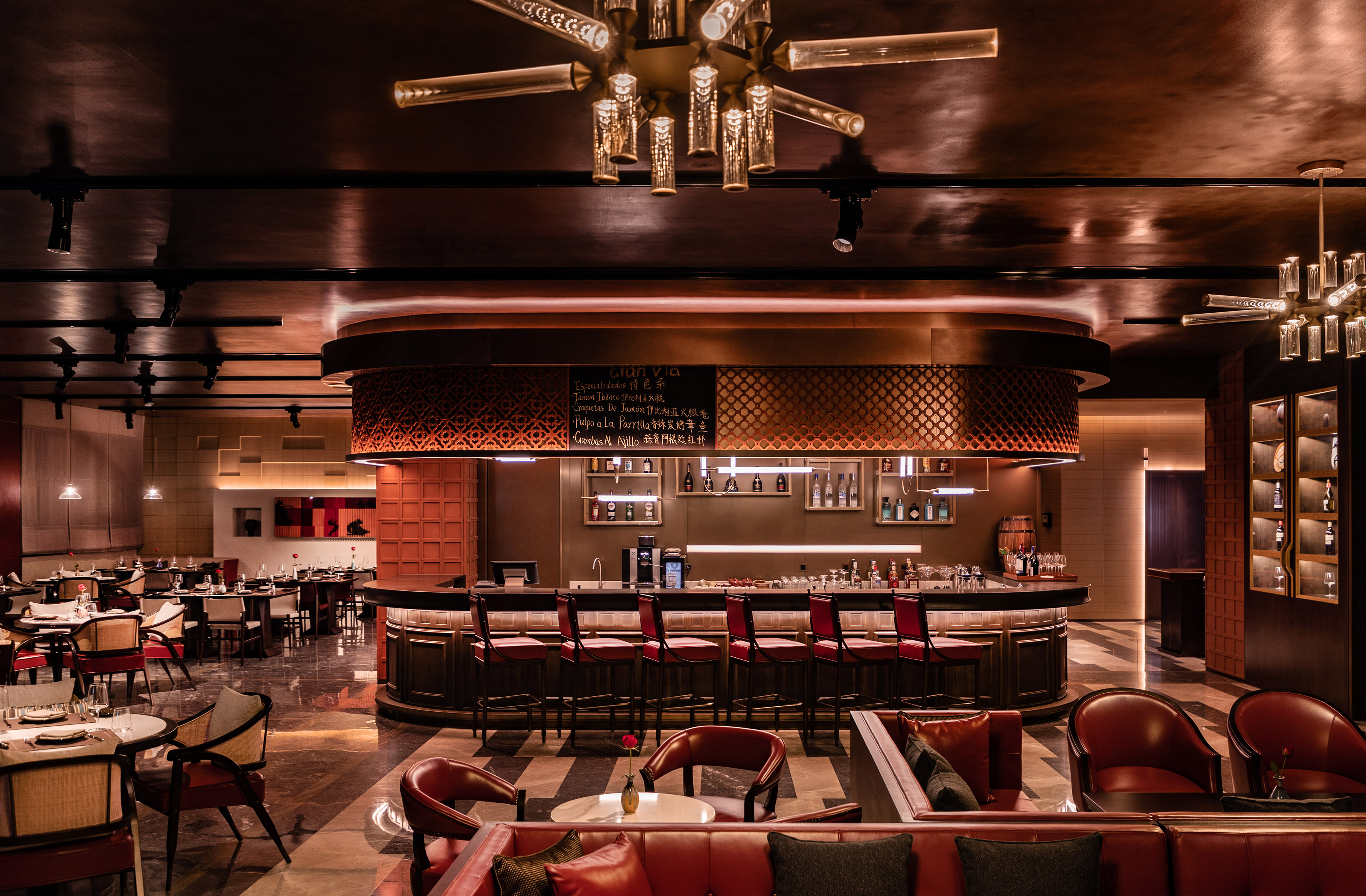 Elegant bar and dining room with red seating and warm lighting.