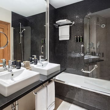 a bathroom with black tile walls and white sinks