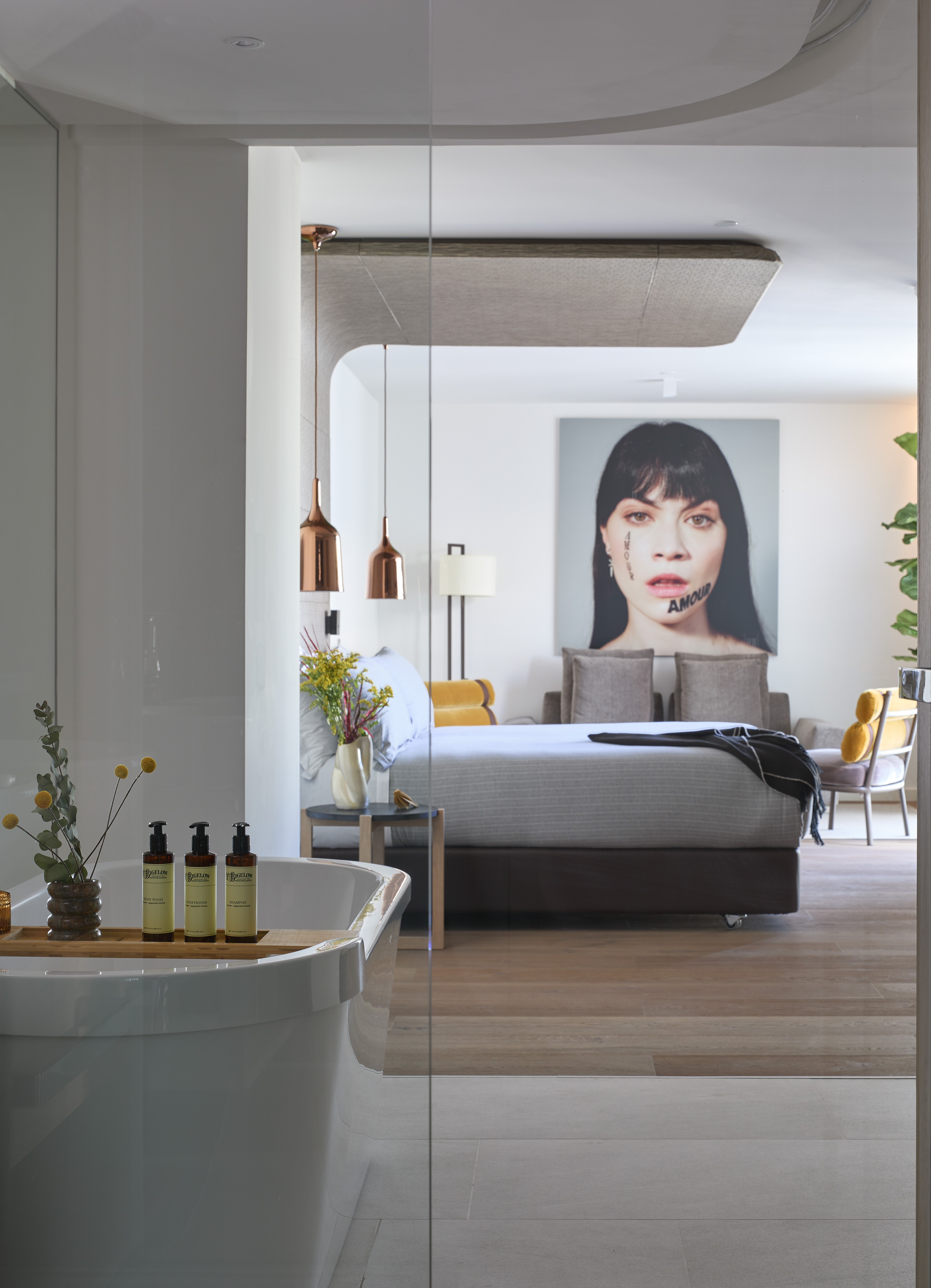 Luxury open-plan bedroom and bath with modern tub, large portrait art.