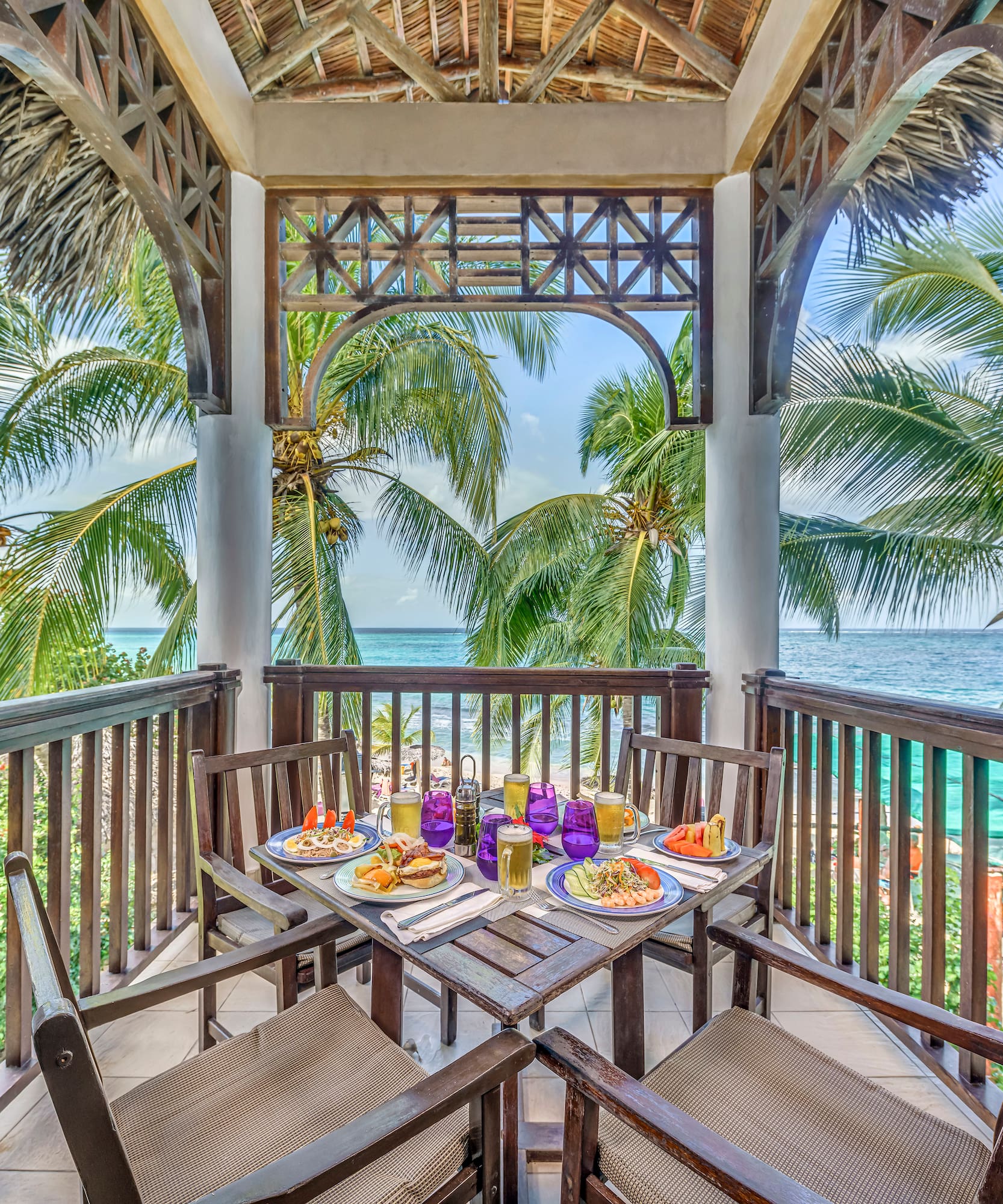 a table with food on it and chairs on a deck overlooking the ocean