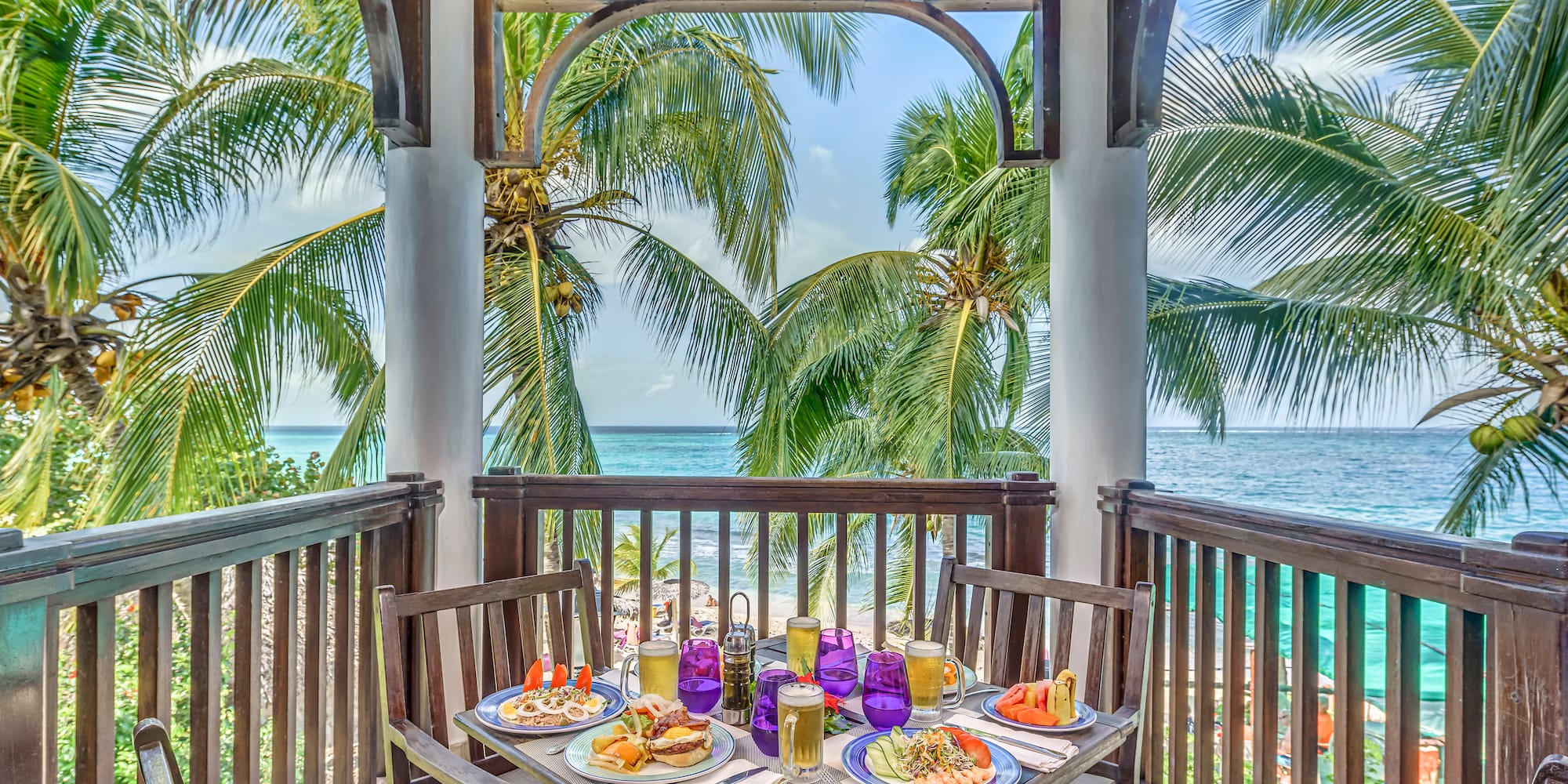 a table with food on it and chairs on a deck overlooking the ocean