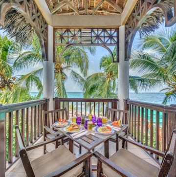 a table with food on it and chairs on a deck overlooking the ocean
