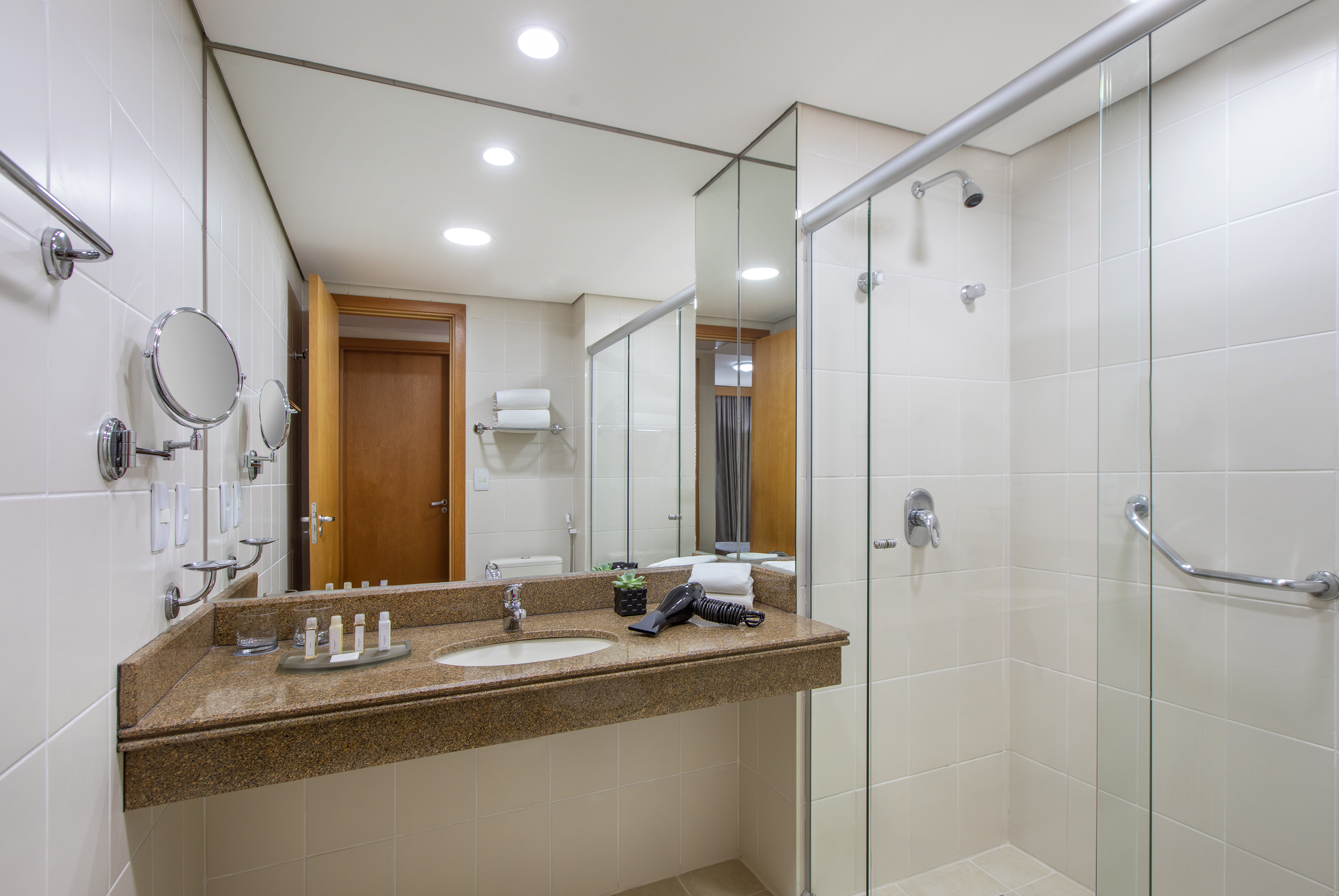Modern bathroom with granite vanity, sink, large mirror, and glass shower.
